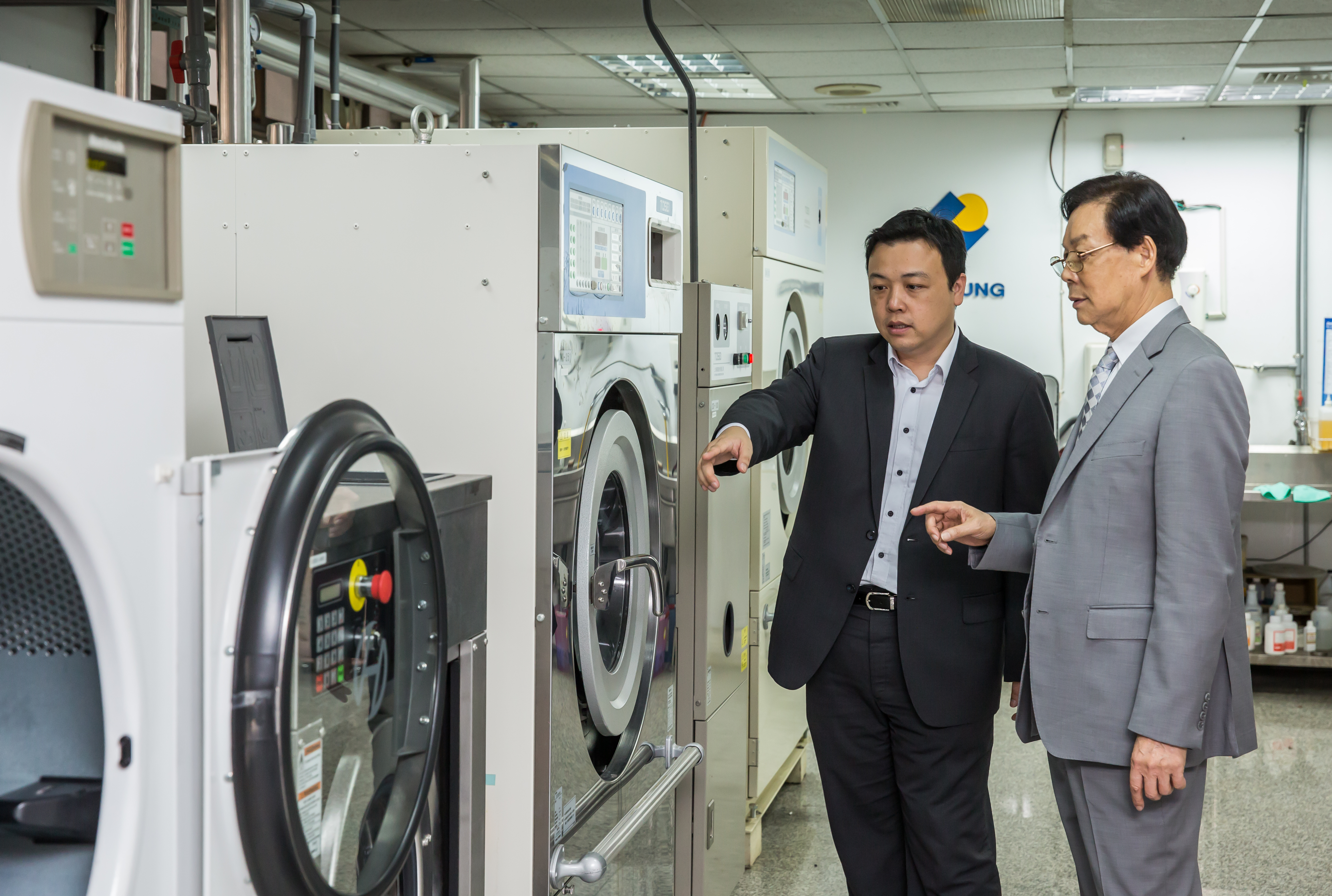 身為代理商，吳明富（右）與吳國華（左）自我要求做到比製造商更懂機器與市場，成美日洗衣設備大廠的重要戰略夥伴。