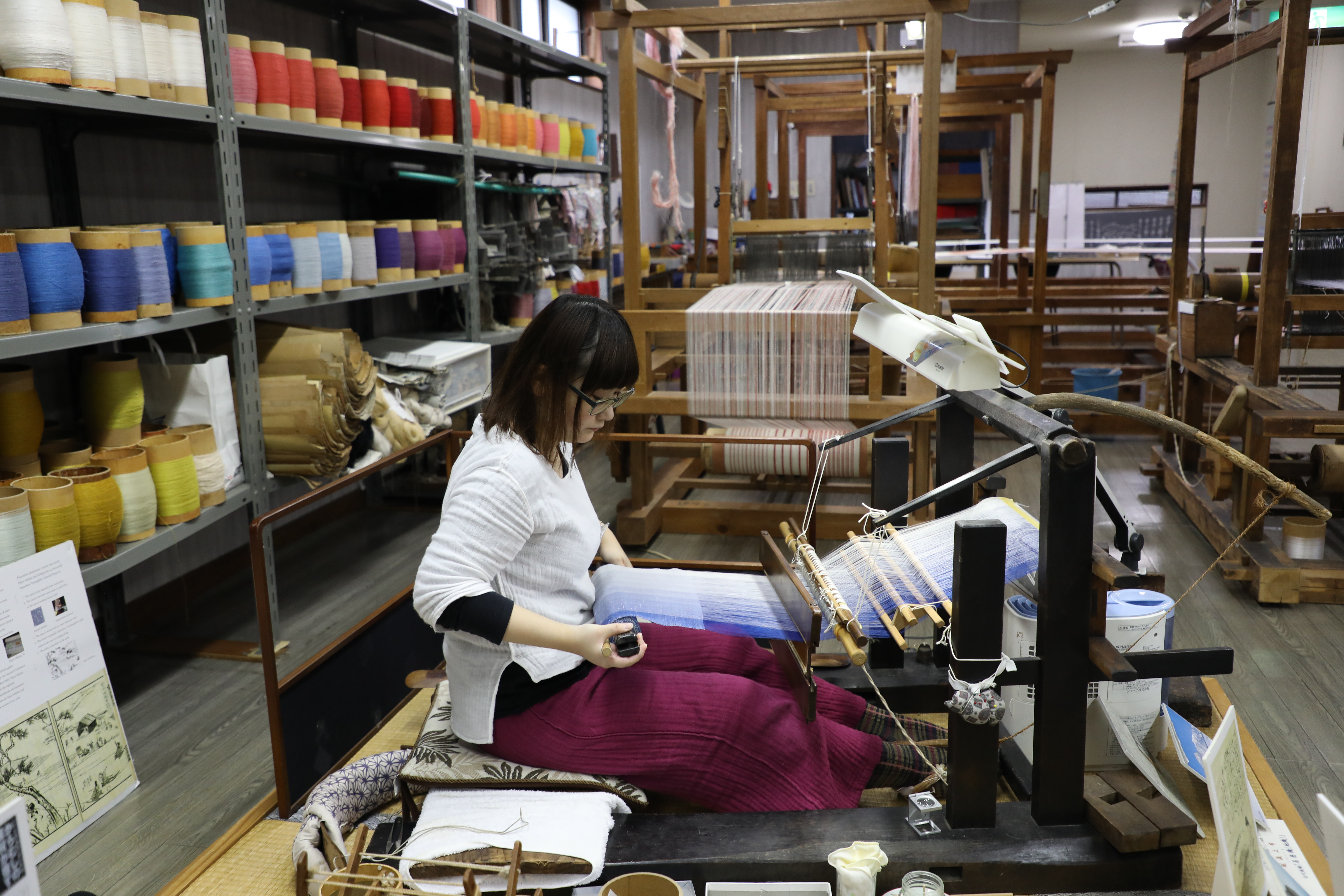 學習手工織布5年的丸山由貴菜，示範如何操作傳統織布機。