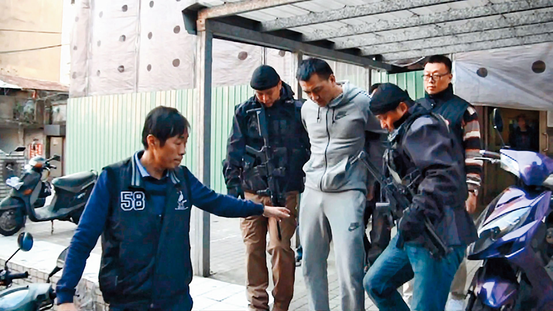 警方將陳福祥（灰衣者）上銬帶回，不費一槍一彈。（東森新聞提供）