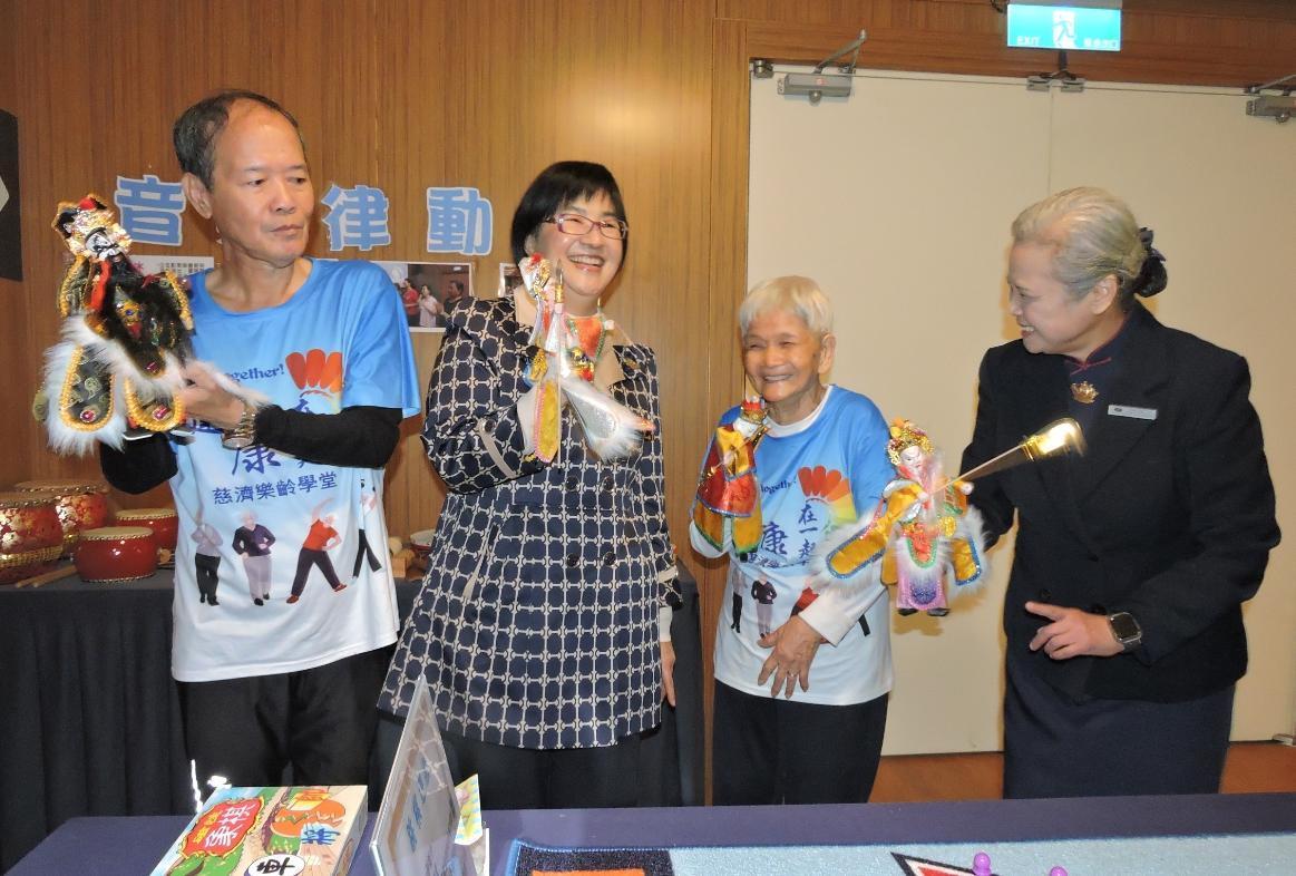 八旬嬤蔡金鳳（右二）從做環保、加入長照據點樂齡學堂、快樂學習做志工過程中「抗老」，靈活展演掌中戲逗樂張錦麗局長（左二）。