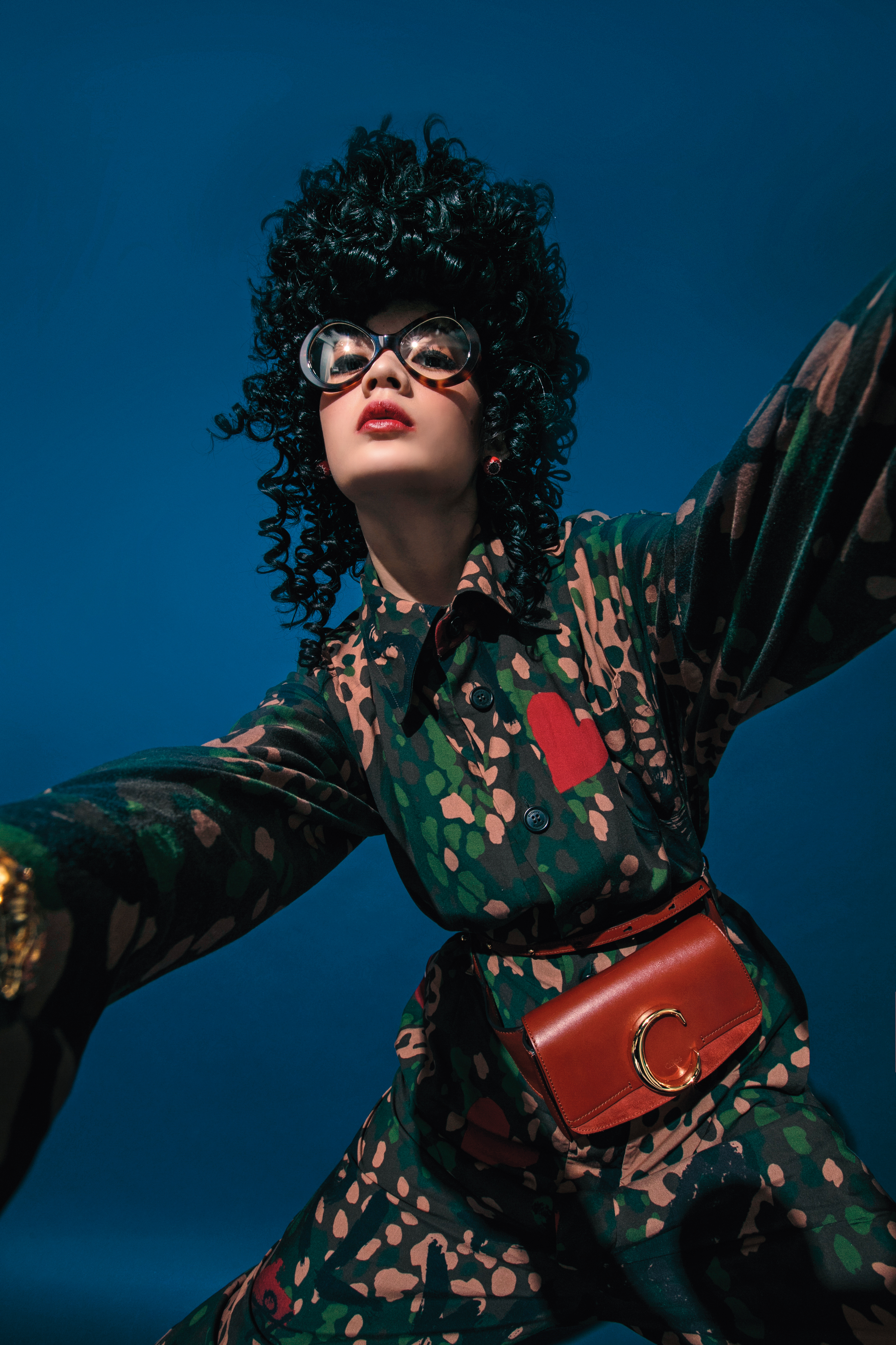 迷彩連身褲 NT$56,400 by Vivienne Westwood／咖啡色粗框眼鏡 NT$19,300 by Chloé／Tribales紅色珍珠及黑水晶耳飾 NT$19,500 by Dior／Chloé C咖啡色腰包 NT$30,600 by Chloé。