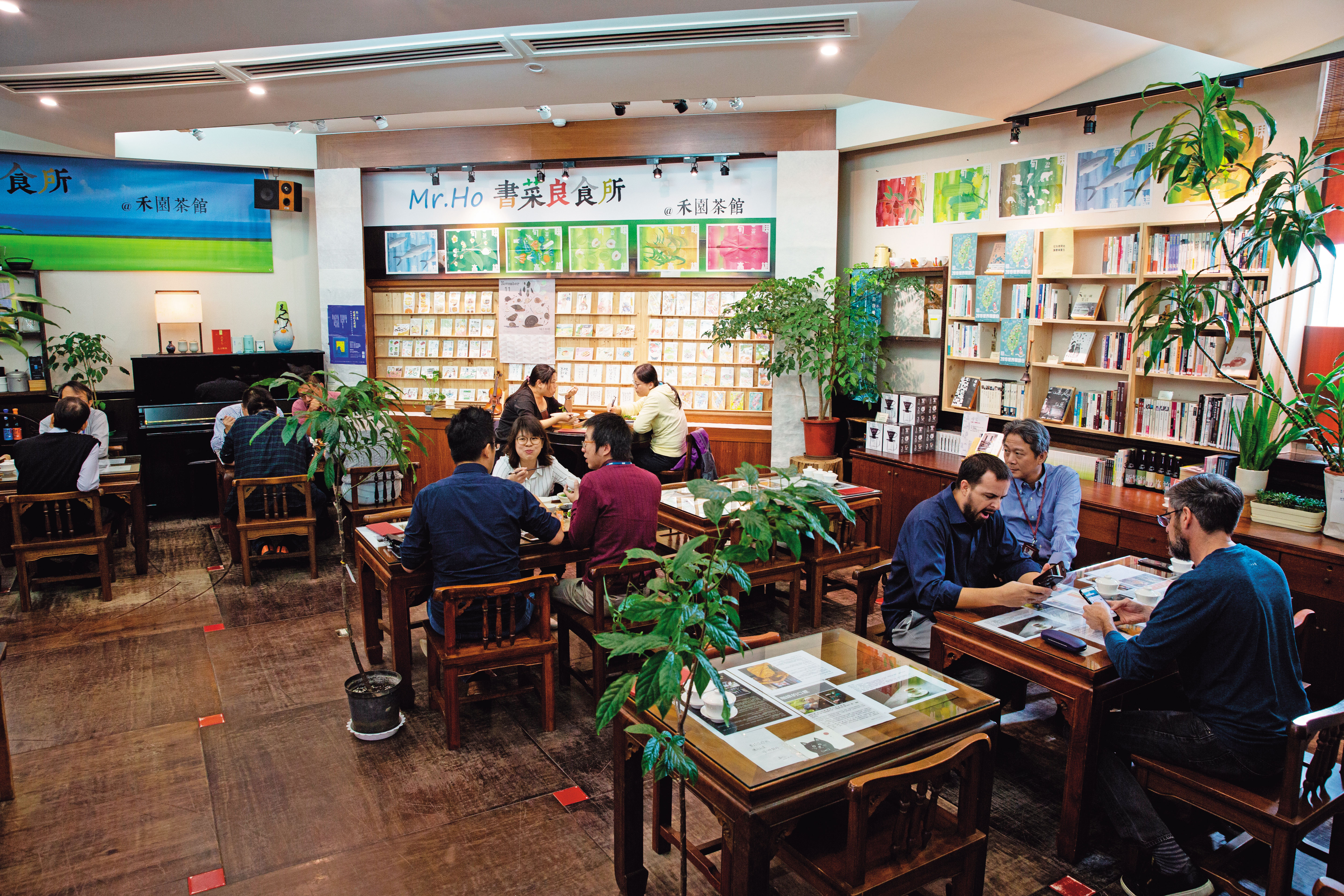 禾園茶館沒有過多華麗裝潢，木質空間以大面積書牆、彩繪明信片與綠色植栽妝點。