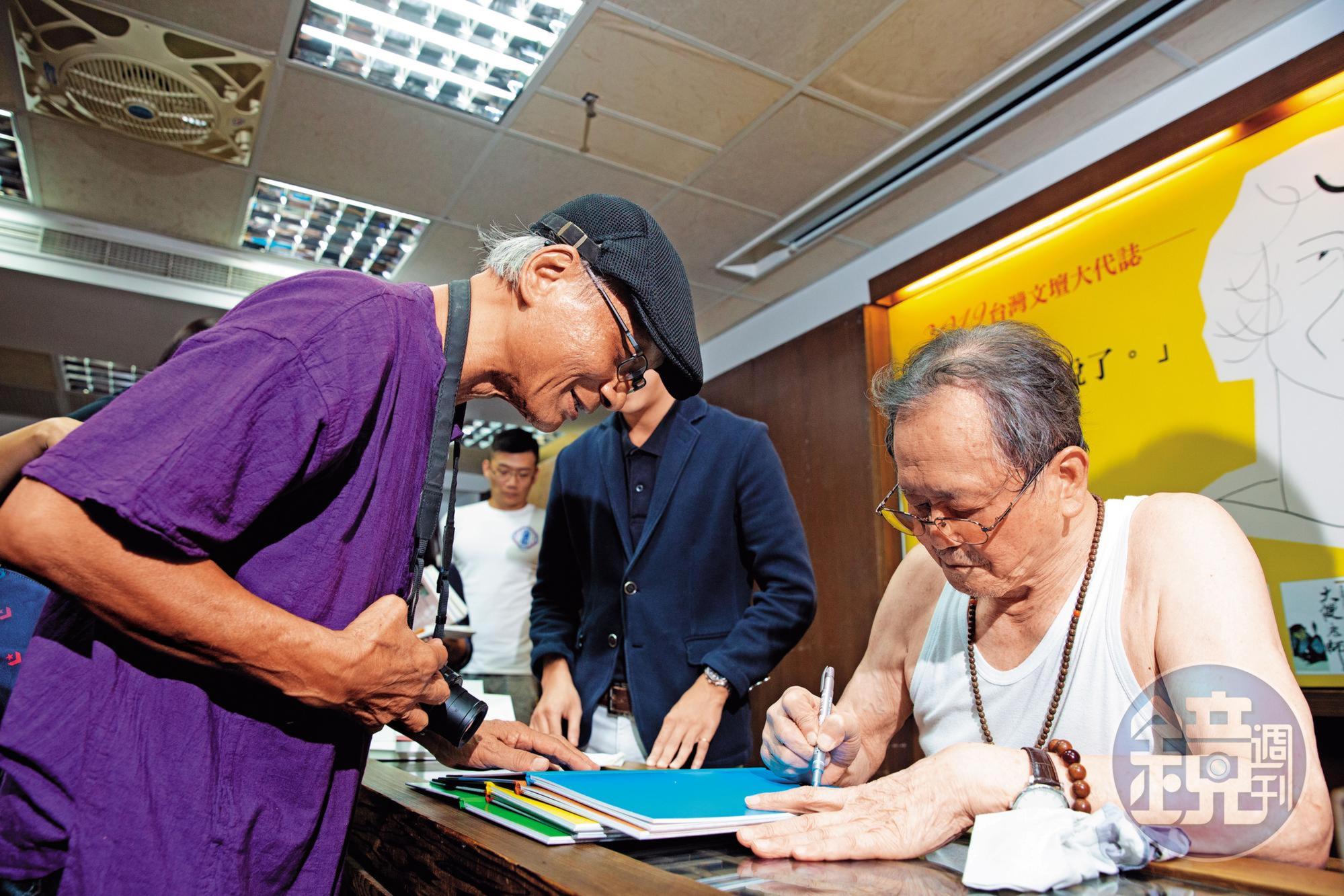 黃春明(右)新書座談會簽得滿頭大汗,索性扒下襯衫,就穿著一件背心振筆疾書。