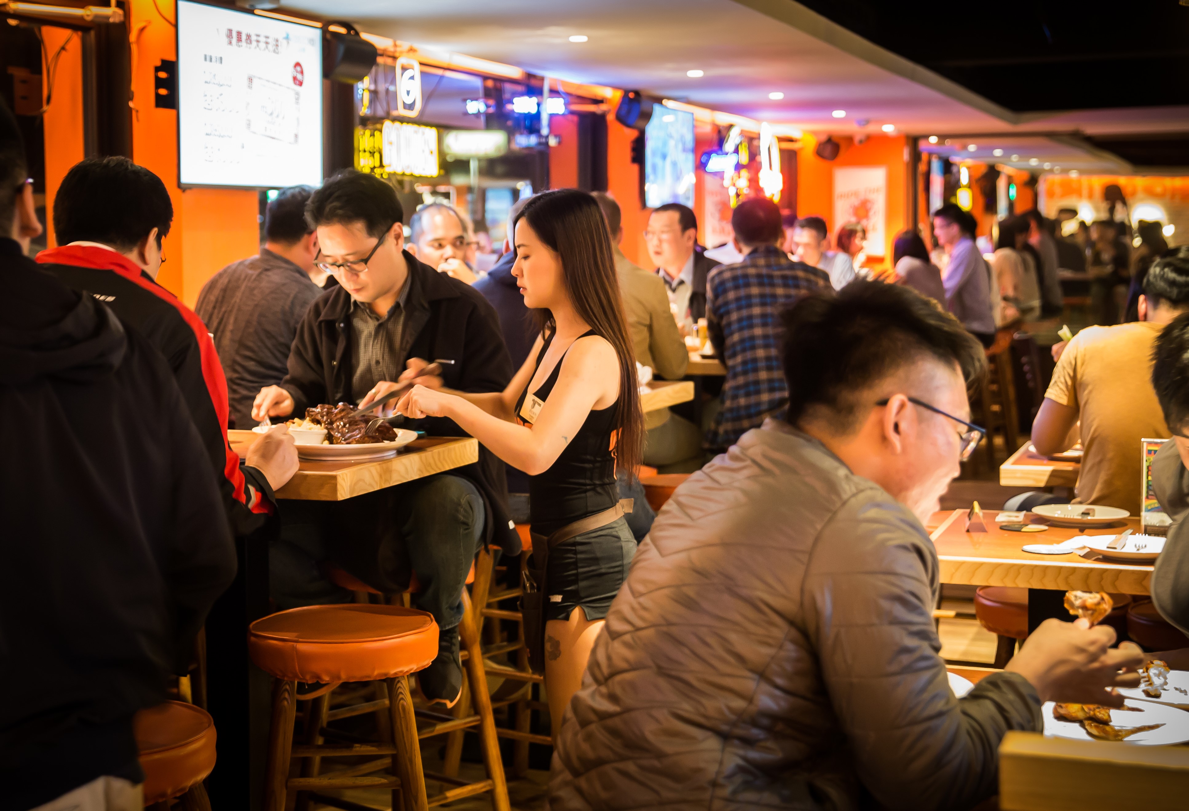 晚餐時間，幾近客滿。Hooters girl正在進行桌邊服務，細心幫客人切肋排。