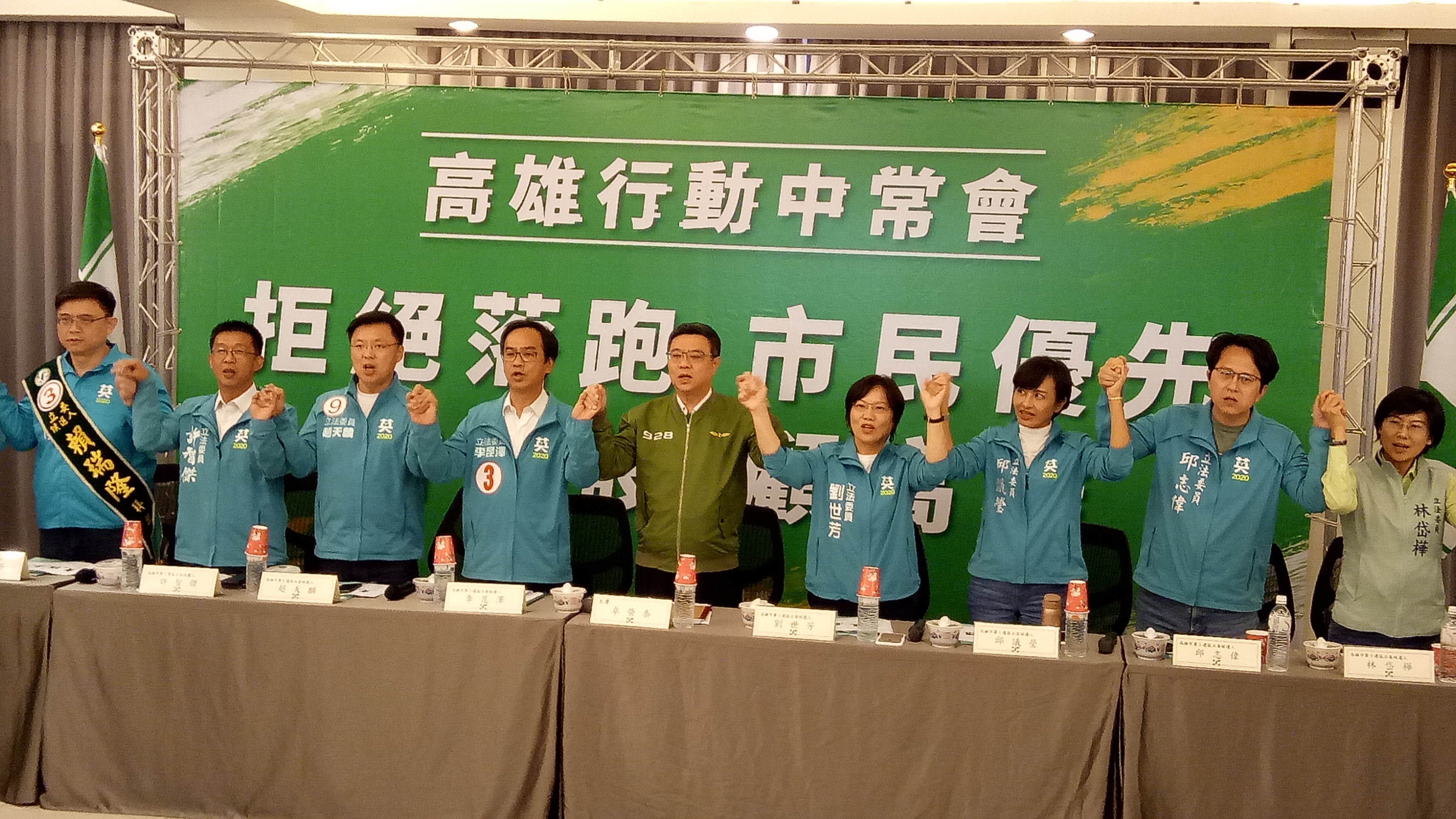 民進黨行動中常會今移師高雄，民進黨主席卓榮泰（中）與8位立委候選人一同攜手喊口號。