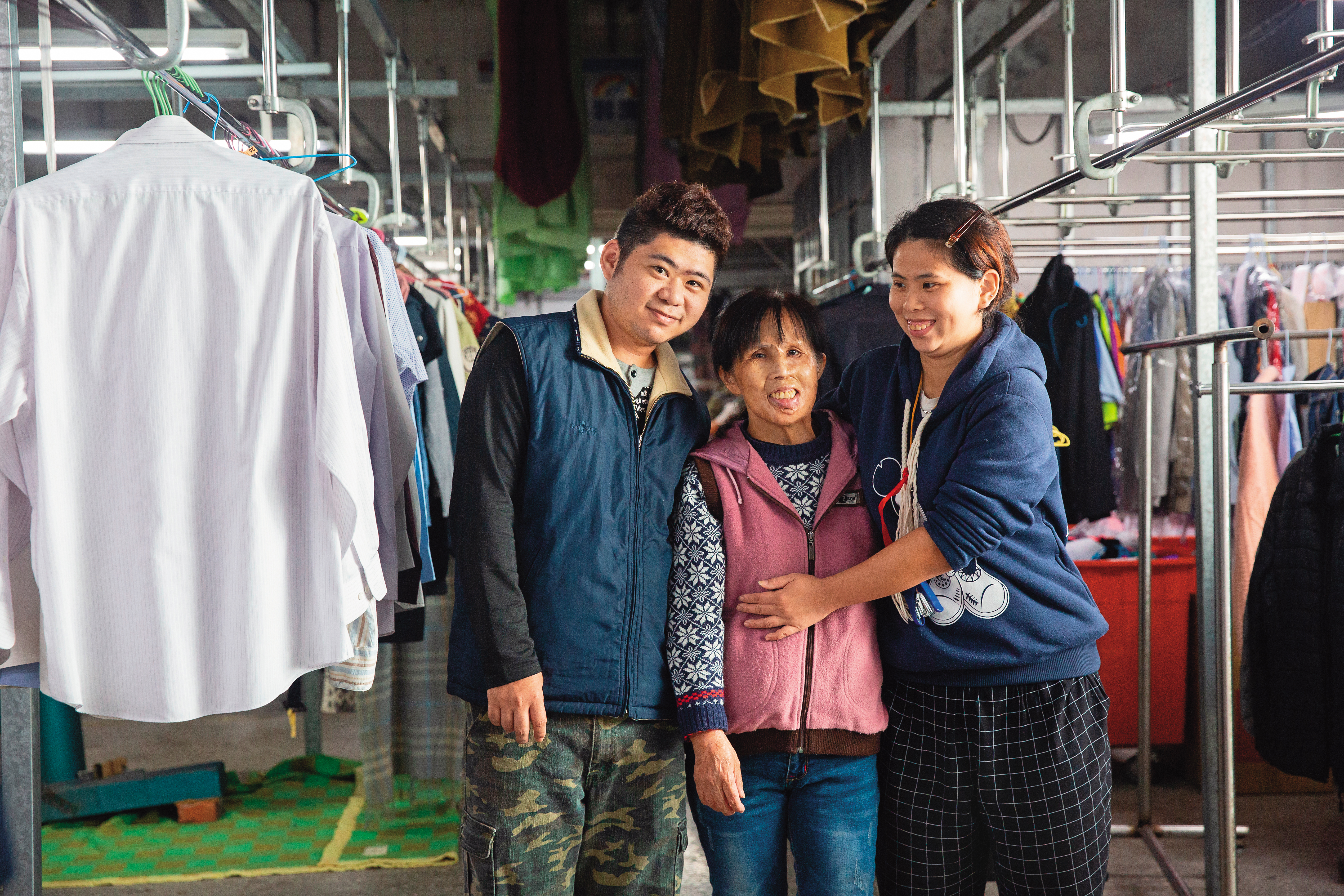 范秀菊（中）與三女兒（右）、小兒子（左）在洗衣工廠一同工作、生活。