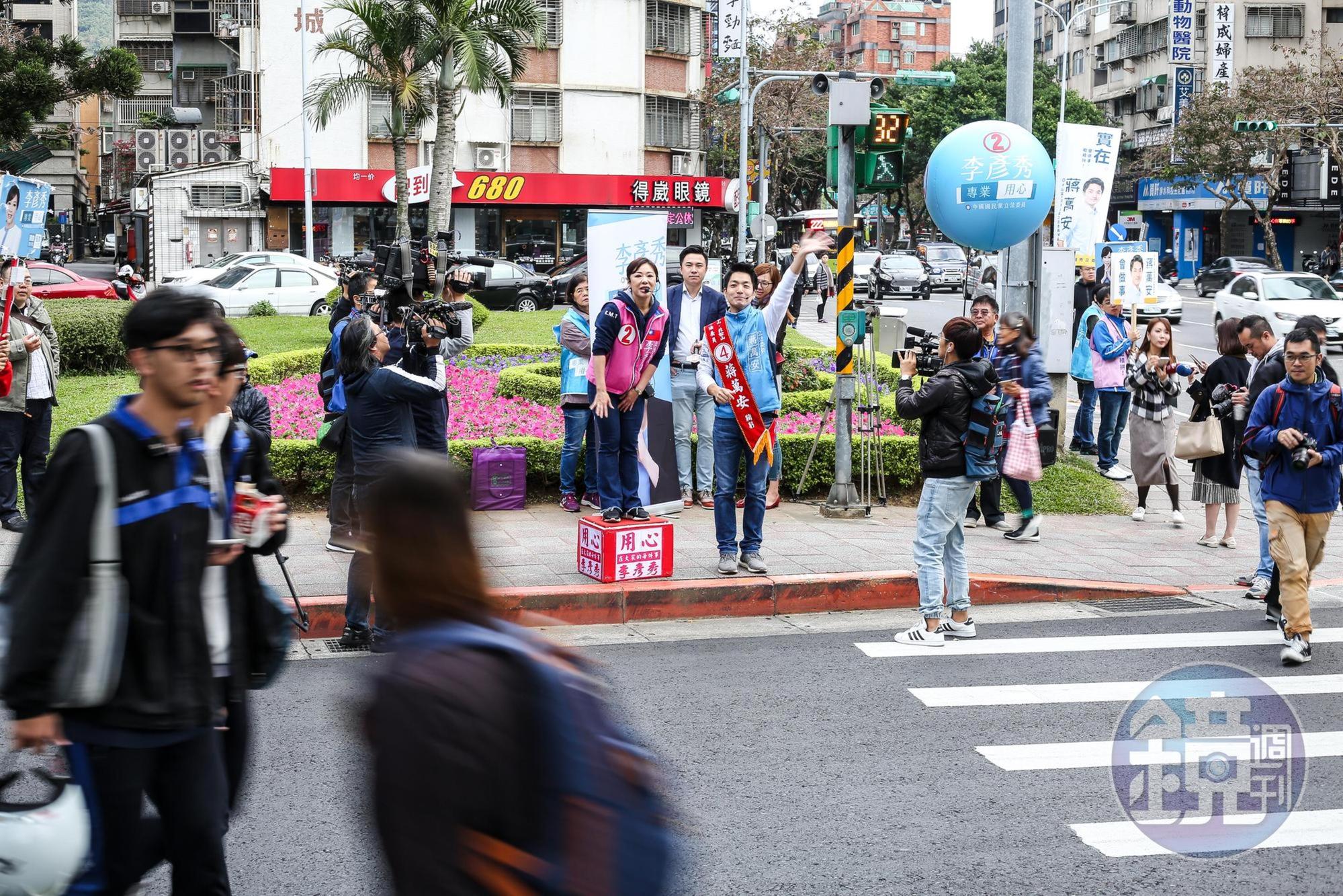  蔣萬安、李彥秀攜手站在內湖路港墘路口，與來往的民眾道早安。