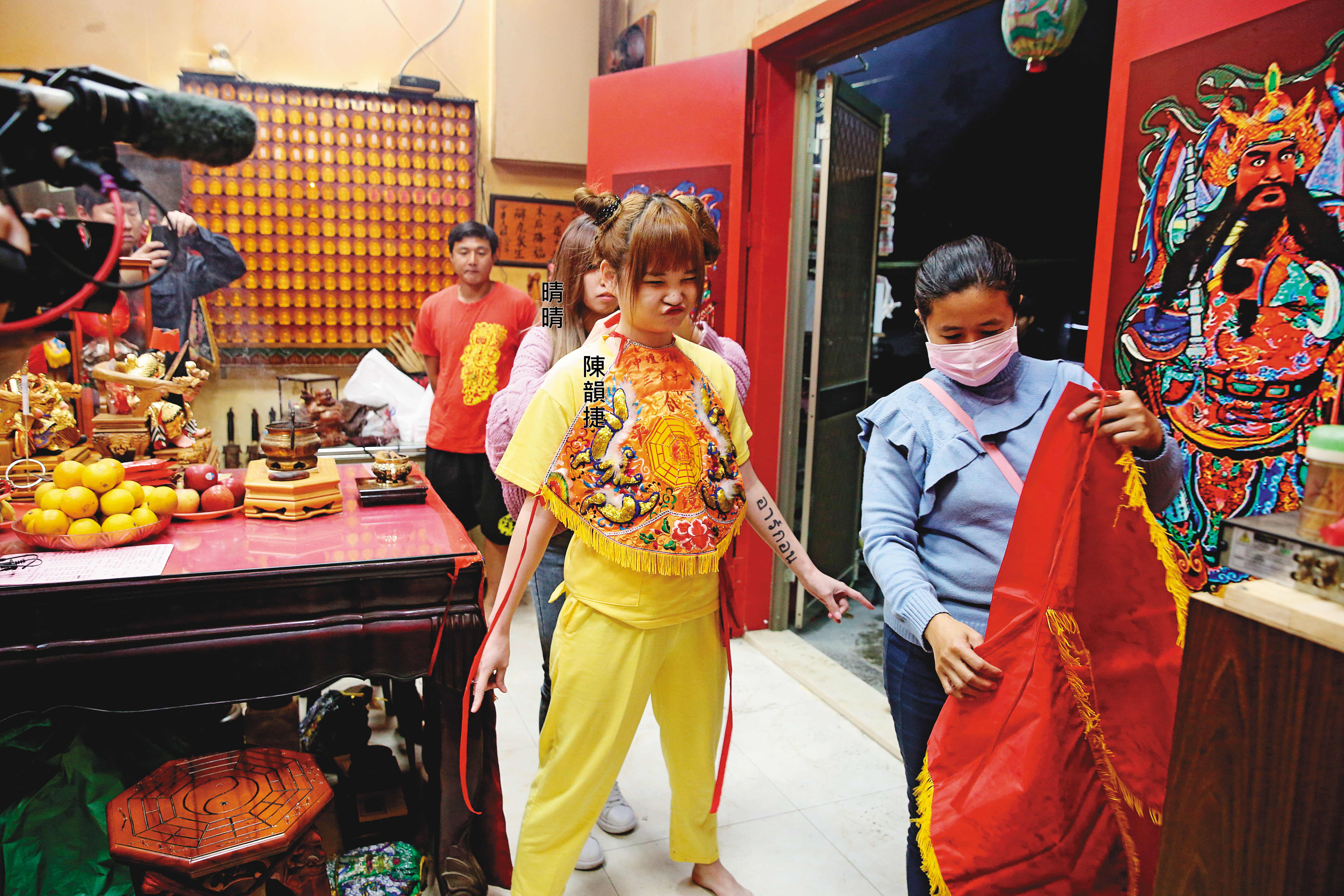 「桌頭」晴晴替正妹乩童陳韻捷圍上肚兜，準備開始辦事。