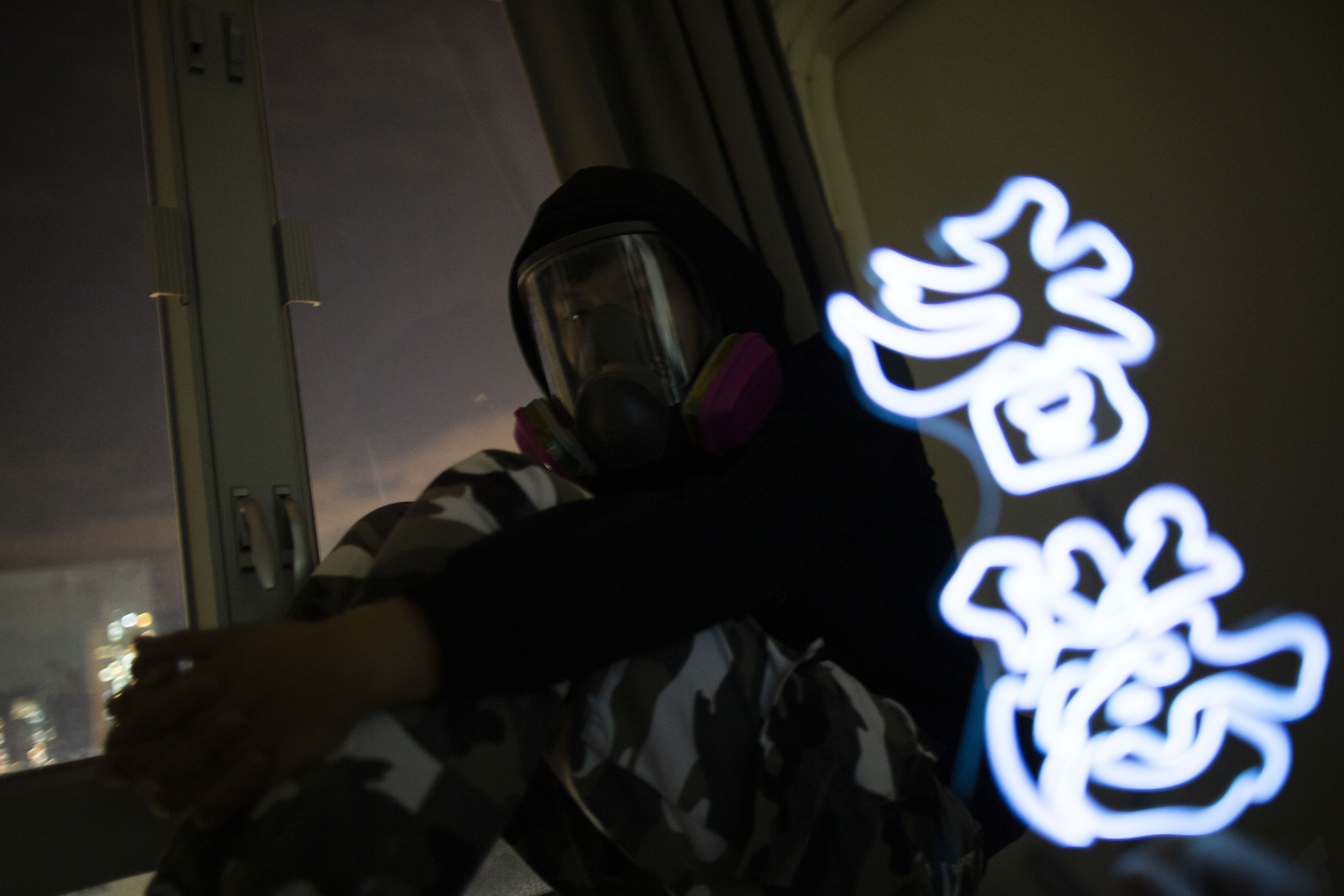 迷彩在民宅接受訪問，一旁的燈「香港」放倒了即為「加油」。