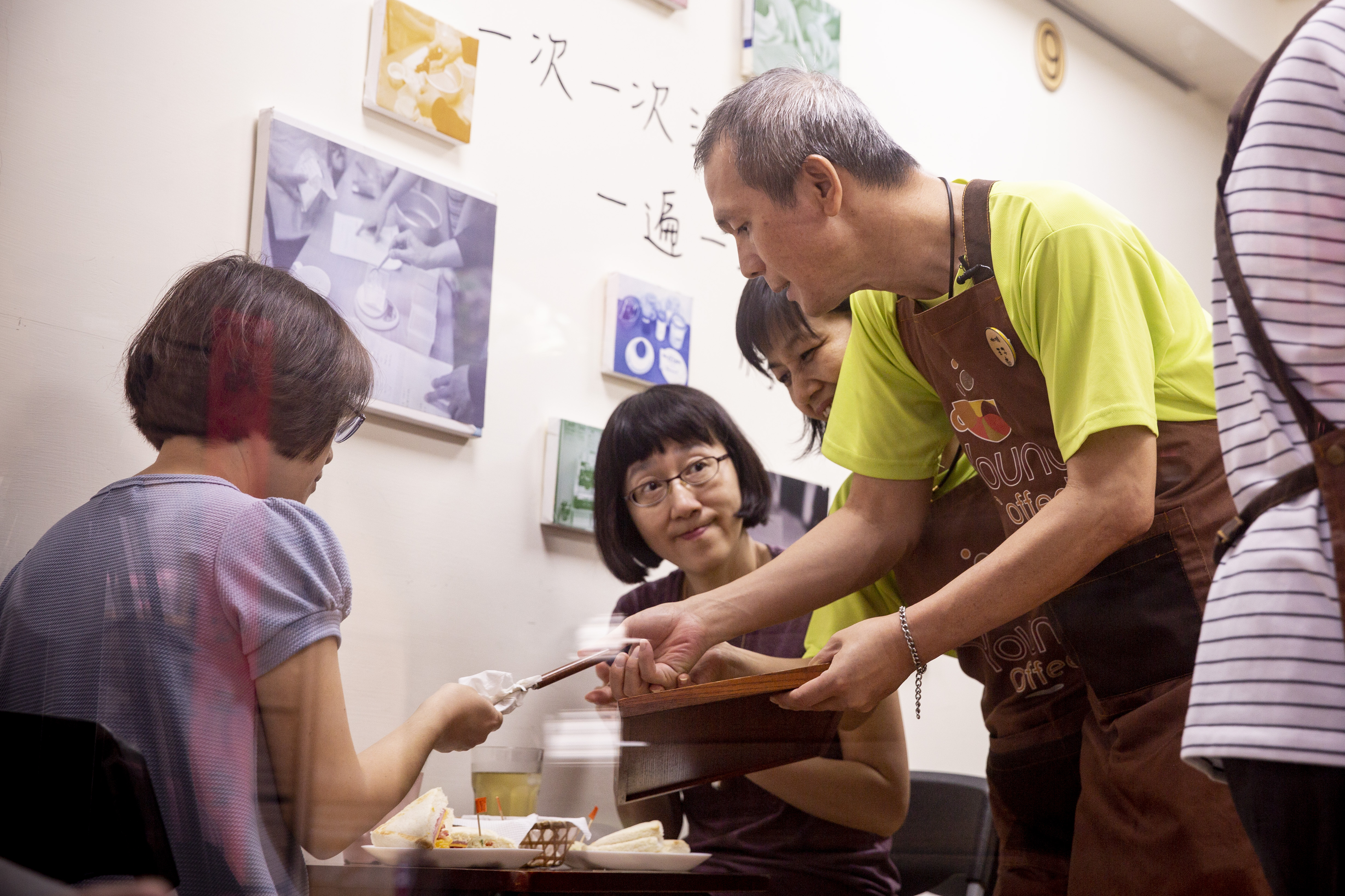 劉鳳蓮（右2）陪著失智的先生林善仁（右1）在咖啡館工作。