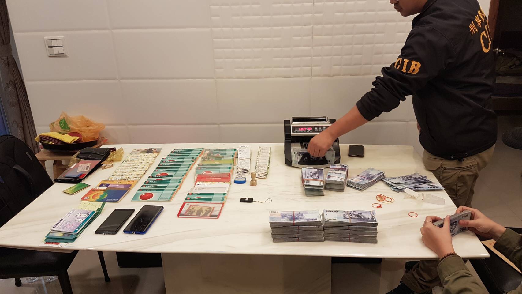 警方查扣現金新台幣852萬、人民幣8萬、越南盾3727萬、U盾、存摺、提款卡、點鈔機等證物。（翻攝畫面）