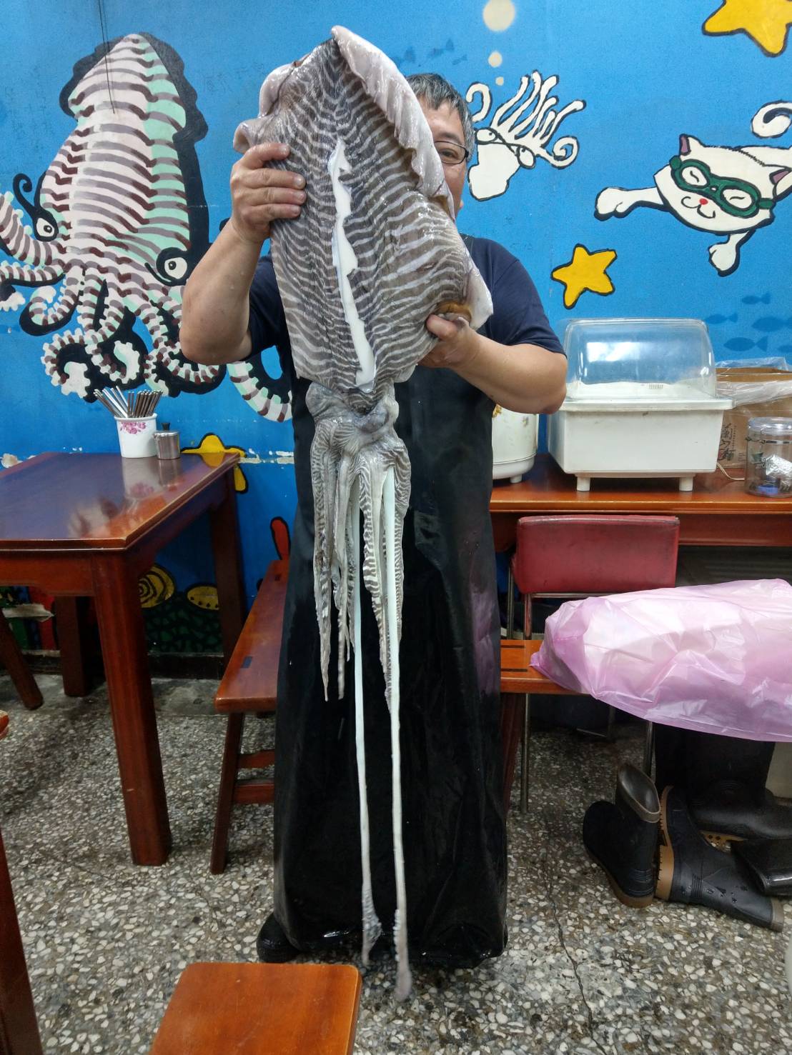 曾記花枝羹第二代老闆曾行正處理整隻生花枝,尺寸相當於一個成年男子身高。(曾行正提供)
