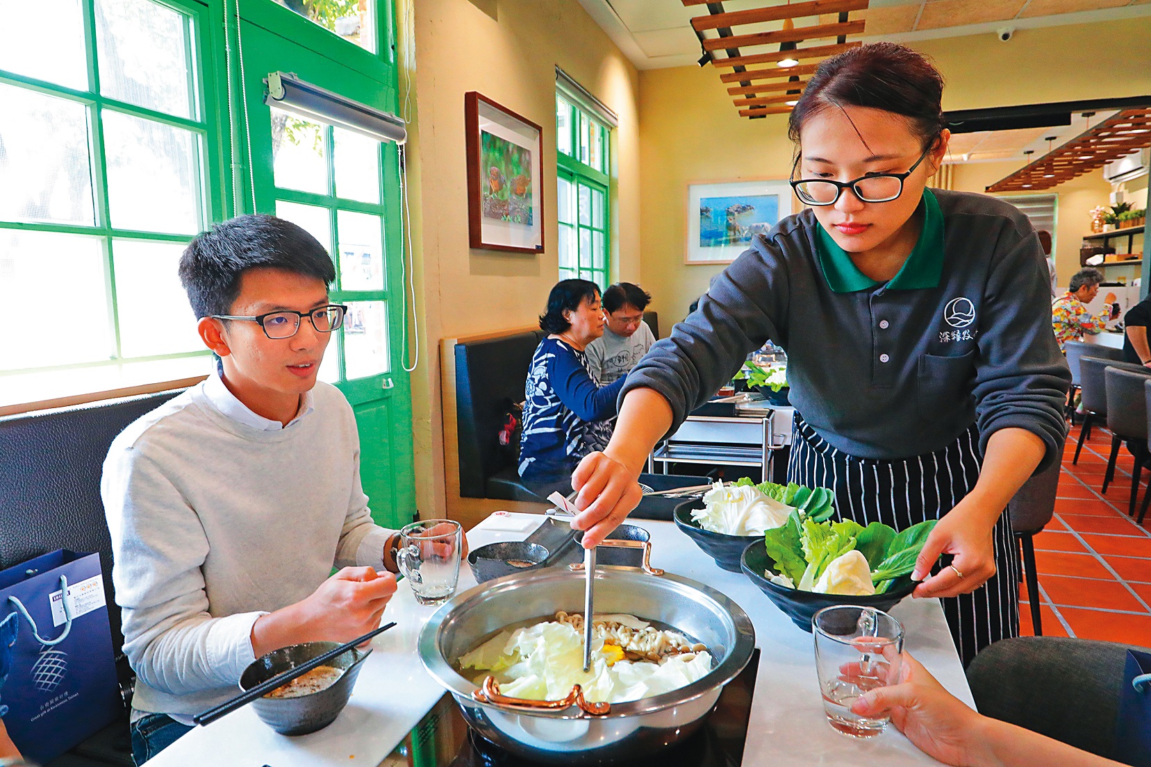 「及水火鍋館」服務人員細心幫客人將食材放入火鍋。