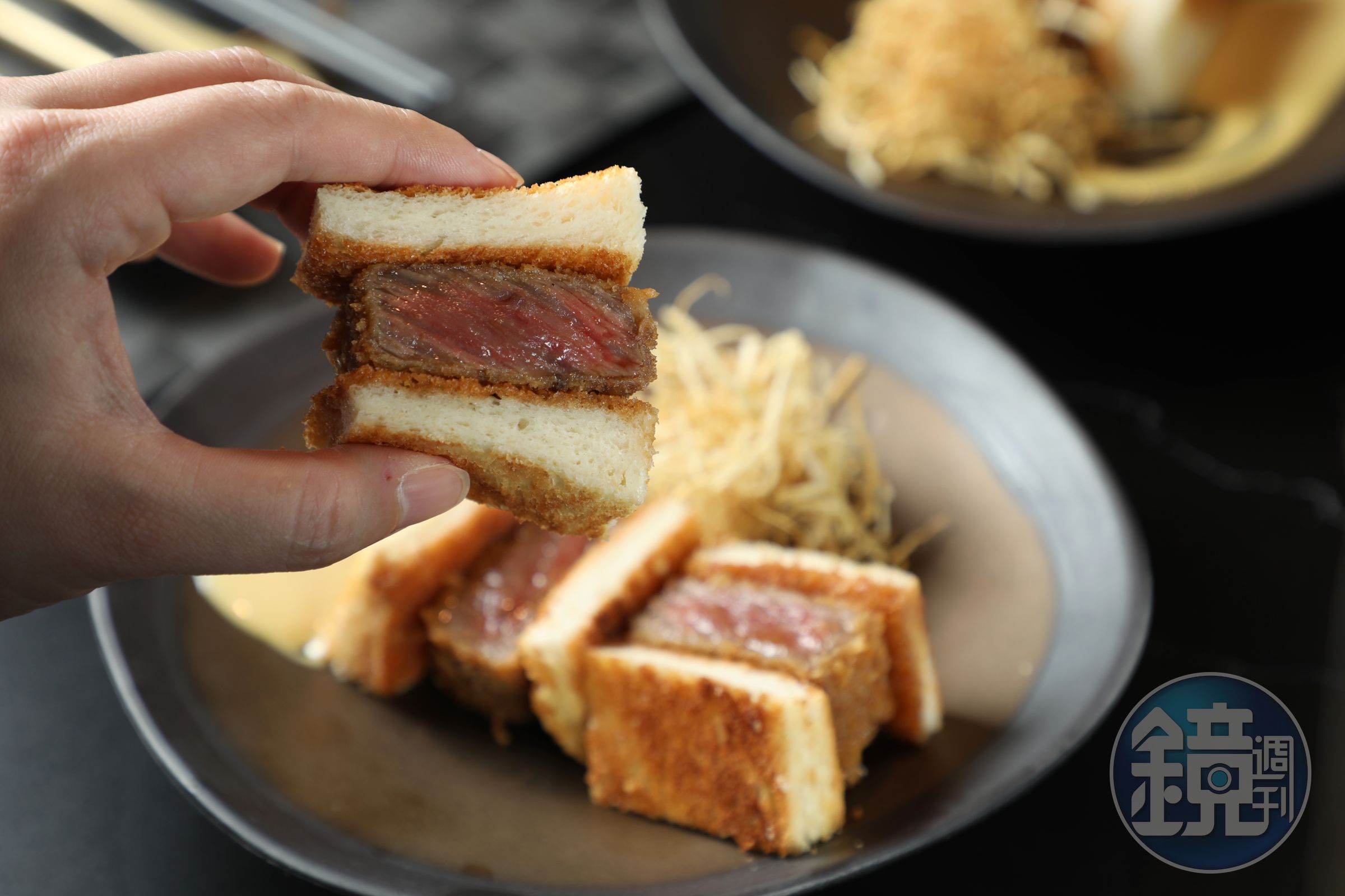 用拇指、食指掐起「A5和牛牛排三明治」，一口咬下，脆、潤、彈多種口感在嘴裡綻放。（搭配1,280元起牛割烹套餐，加價680元／份、單點780元／份）
