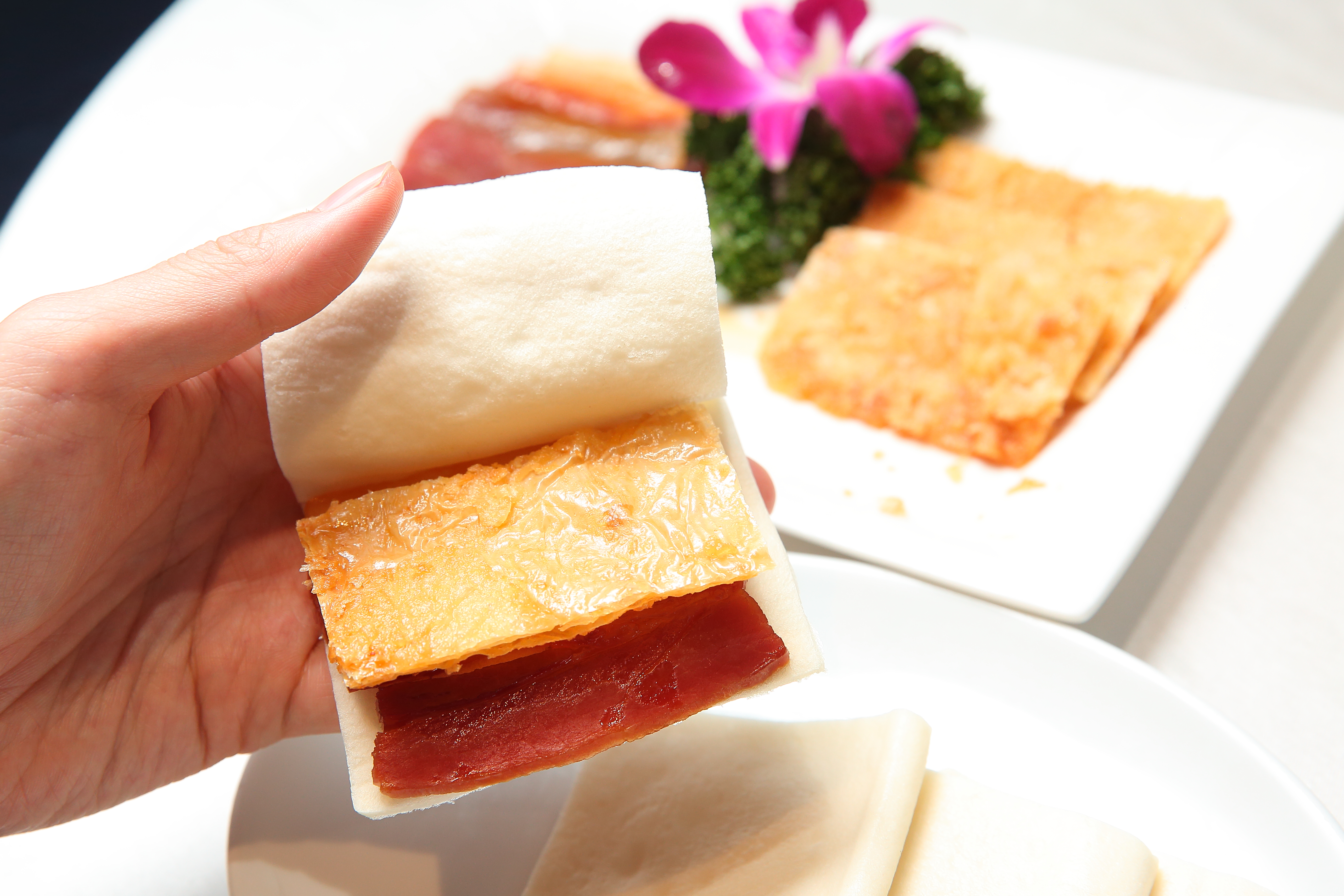 彭長貴發明的富貴雙方，火腿用棉糖、蜂蜜中和調製後悶烤，熟成入味出爐，搭上香酥脆口的烤素方、鬆軟的手工麵皮入口，Q軟中帶酥脆、鹹鮮滋味。（彭園創始店，100元／片）