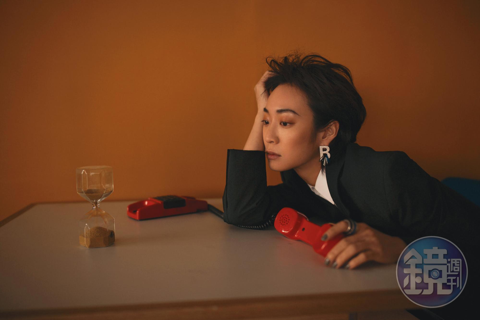 黑色西裝外套 NT$81,900 by BOTTEGA VENETA；白色襯衫 NT$17,500 by CELINE；字母多圈耳環 價格店洽 by BALENCIAGA；多圈戒指 NT$14,100 by BALENCIAGA。