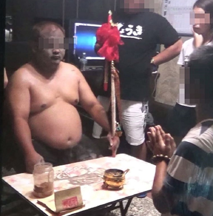 神棍陳兄作法事，郭女在旁隨侍，與弟弟郭男跪在案前。（翻攝畫面）