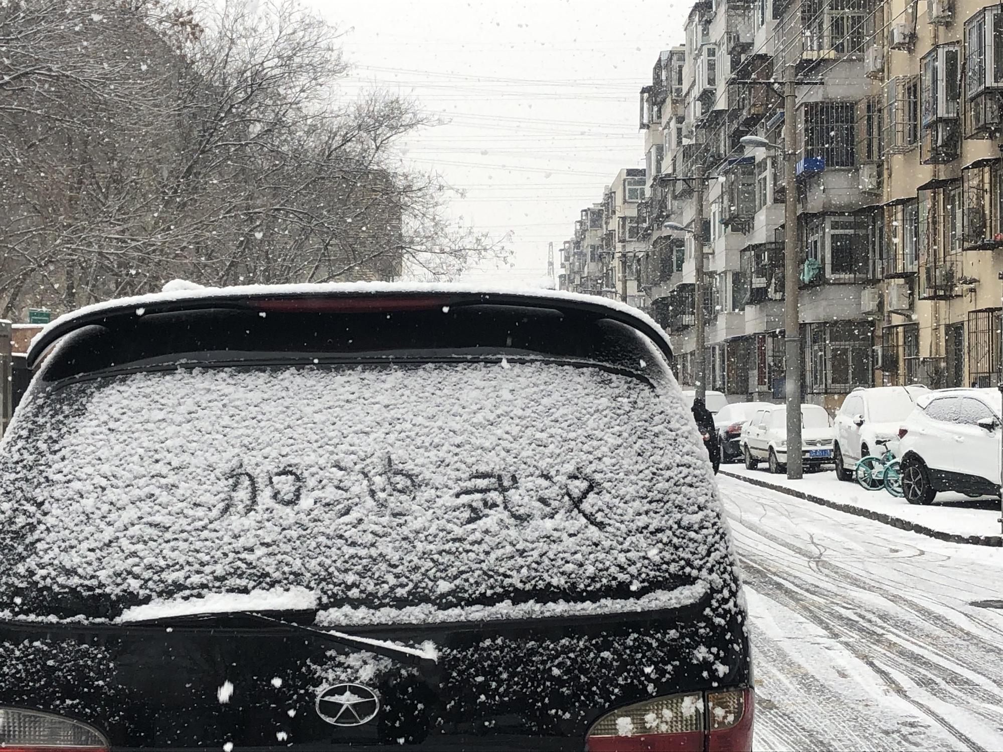 北京降大雪,路邊汽車車窗積雪被人寫上加油打氣的口號(東方IC)