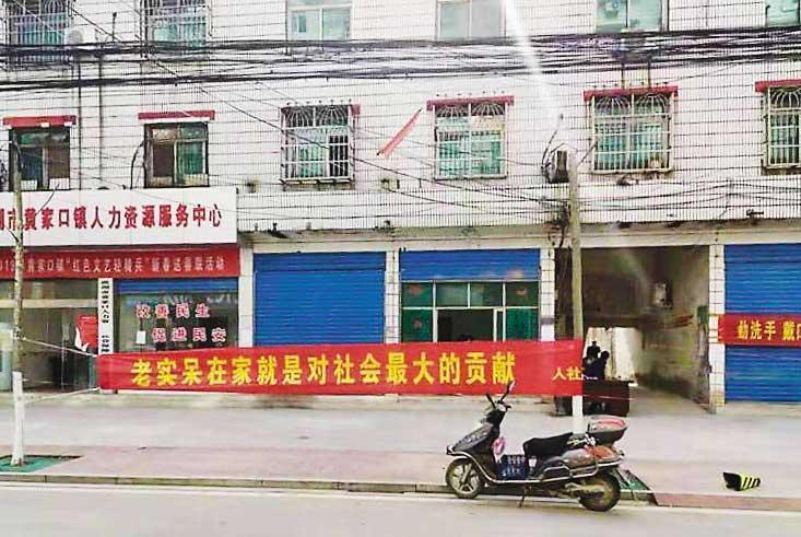 余小魚的太太娘家在洪湖,當地提倡防控疫情,處處張貼標語,圖為其中一張防疫標語條幅,寫著「老實呆(待)在家就是對社會最大的貢獻」。(翻攝《人民網》)