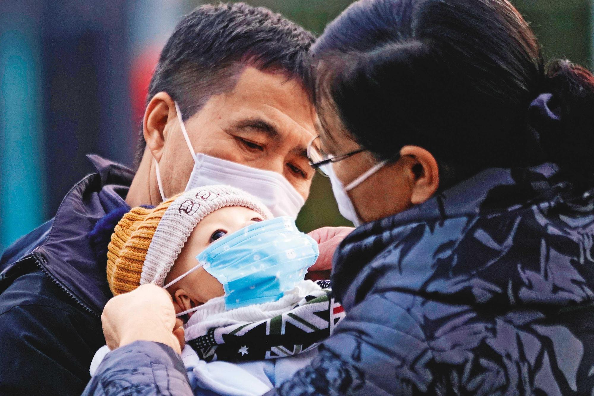 武漢肺炎造成人人自危,圖為大陸民眾替孩子戴上兒童口罩。(達志影像)