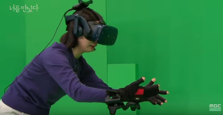 紀錄片中，母親戴著VR眼鏡和觸控手套站在綠幕前和女兒見面。（翻攝Youtube《I Met You》影片）