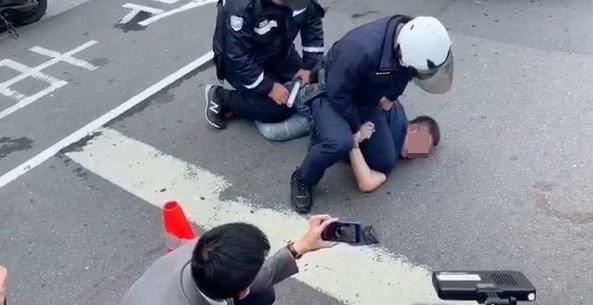 林男因交通堵塞又起行車糾紛,情緒失控大暴走,對記者和警察動粗,遭壓制在地。(翻攝畫面)