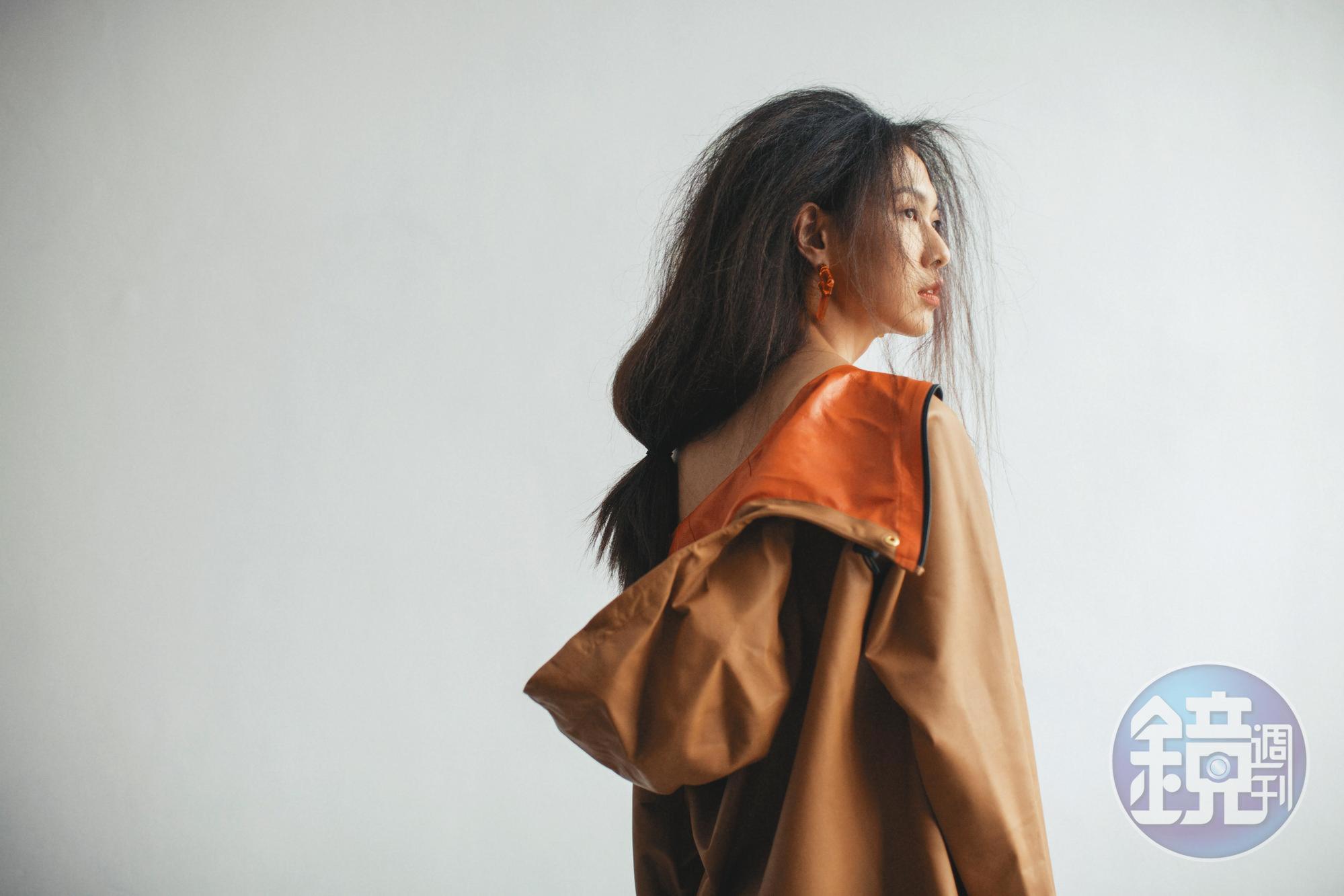 蜜糖棕小牛皮抽繩連帽洋裝 NT$237,500 by Bottega Veneta;設計耳環 NT$19,800 by FENDI。