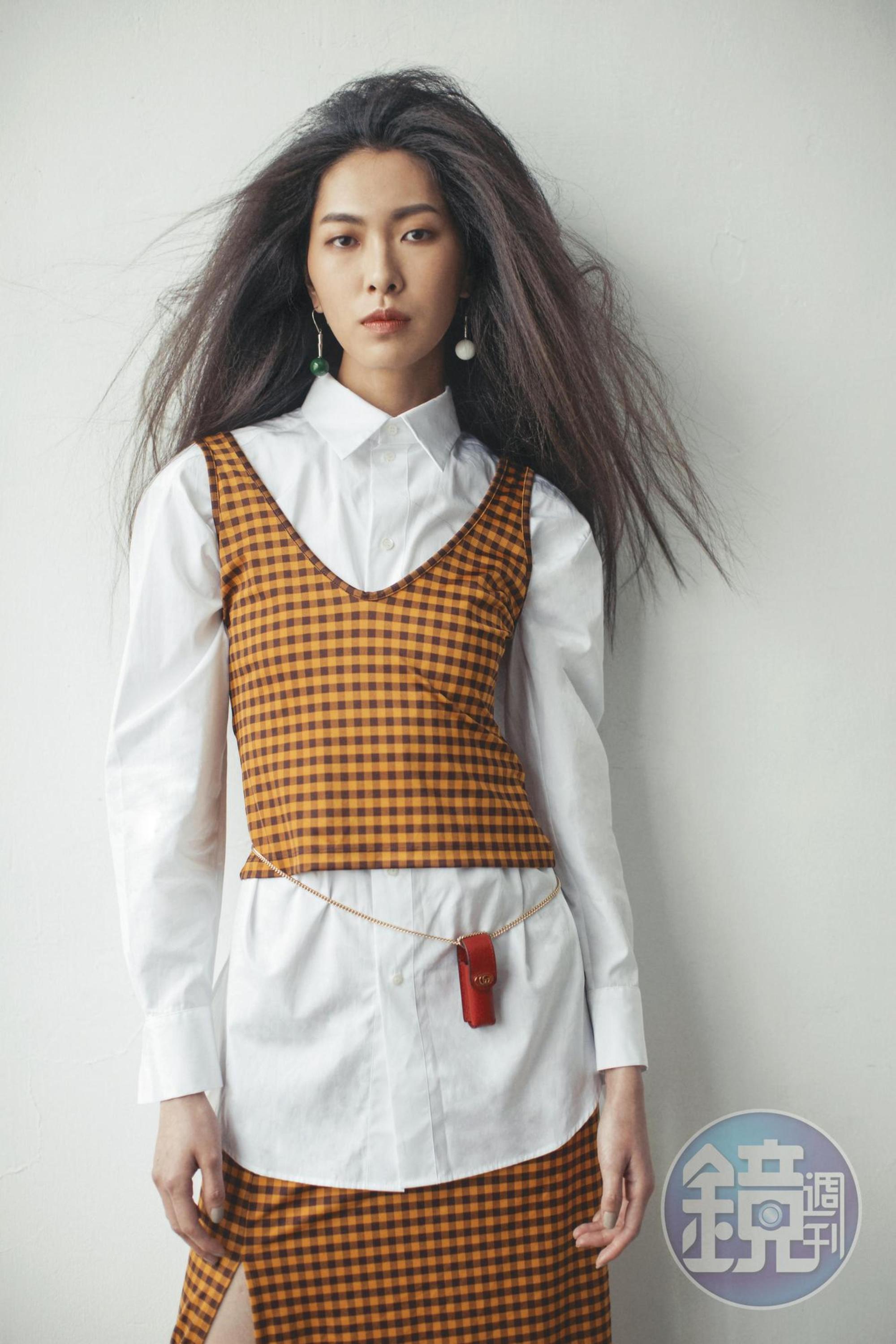 白色襯衫 NT$48,000 by Dior;格紋背心 價格店洽by FENDI;格紋開衩裙 價格店洽by FENDI;玉石耳環 NT$13,800 by 夏姿;紅色鍊帶口紅包 NT$11,000 by GUCCI。