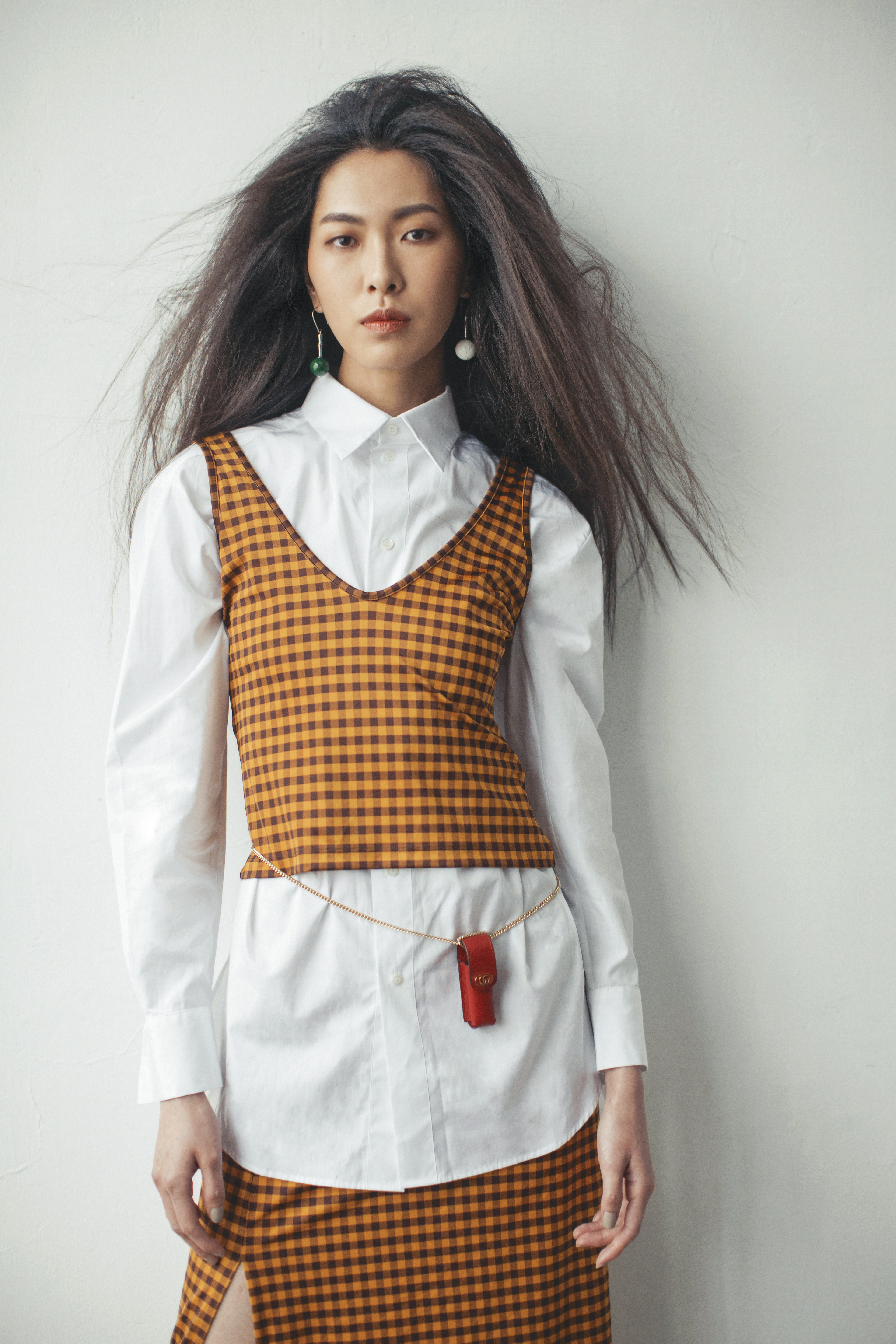 白色襯衫 NT$48,000 by Dior;格紋背心 價格店洽by FENDI;格紋開衩裙 價格店洽by FENDI;玉石耳環 NT$13,800 by 夏姿;紅色鍊帶口紅包 NT$11,000 by GUCCI。