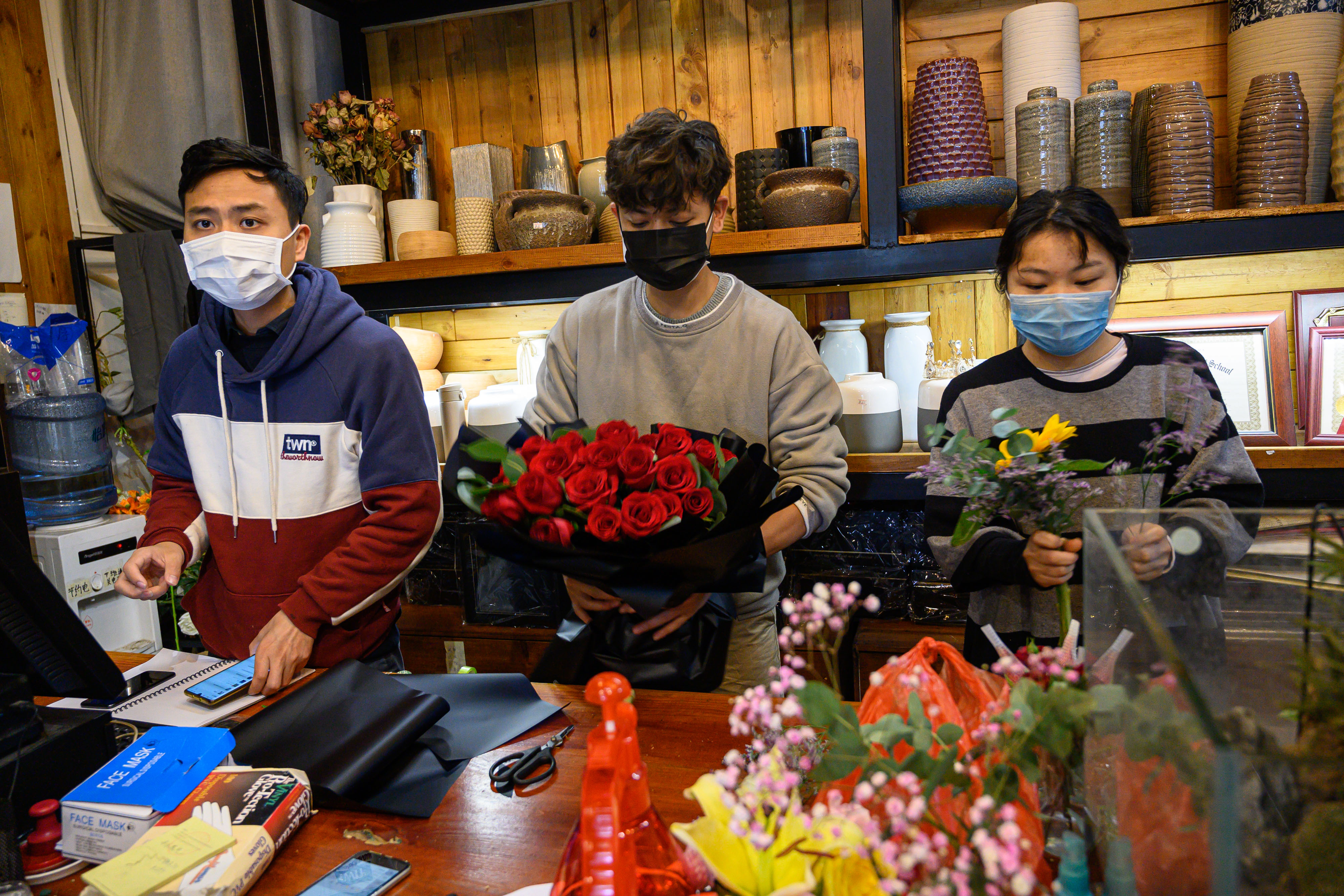 花店員工在情人節忙碌打包花束不忘防疫。（東方IC）