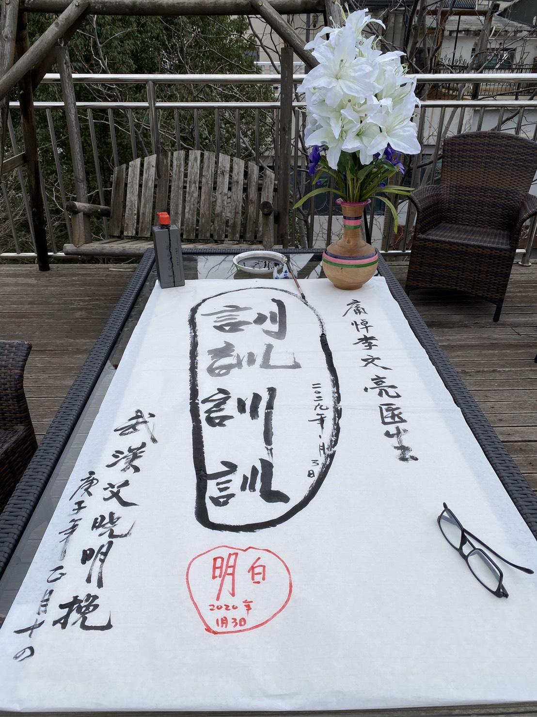 艾曉明在家中陽台寫字悼念被稱為吹哨人、遭警察訓誡後染疫過世的醫生李文亮。(艾曉明提供)