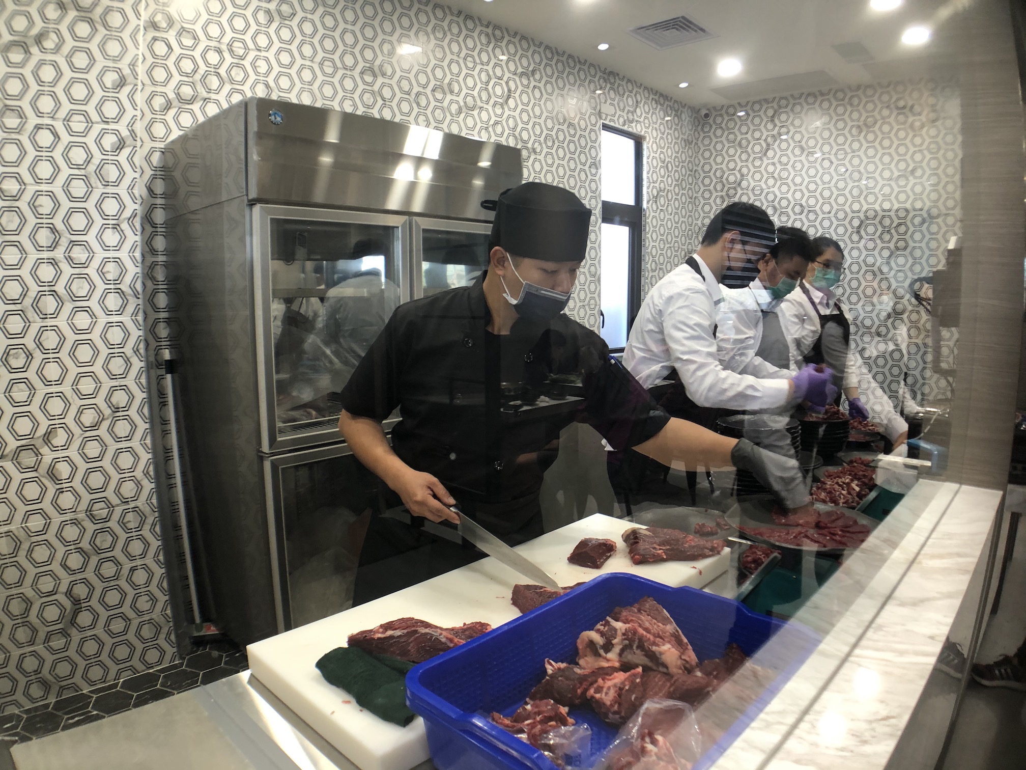 隔著玻璃可見切肉師傅埋首工作，過程乾淨透明。