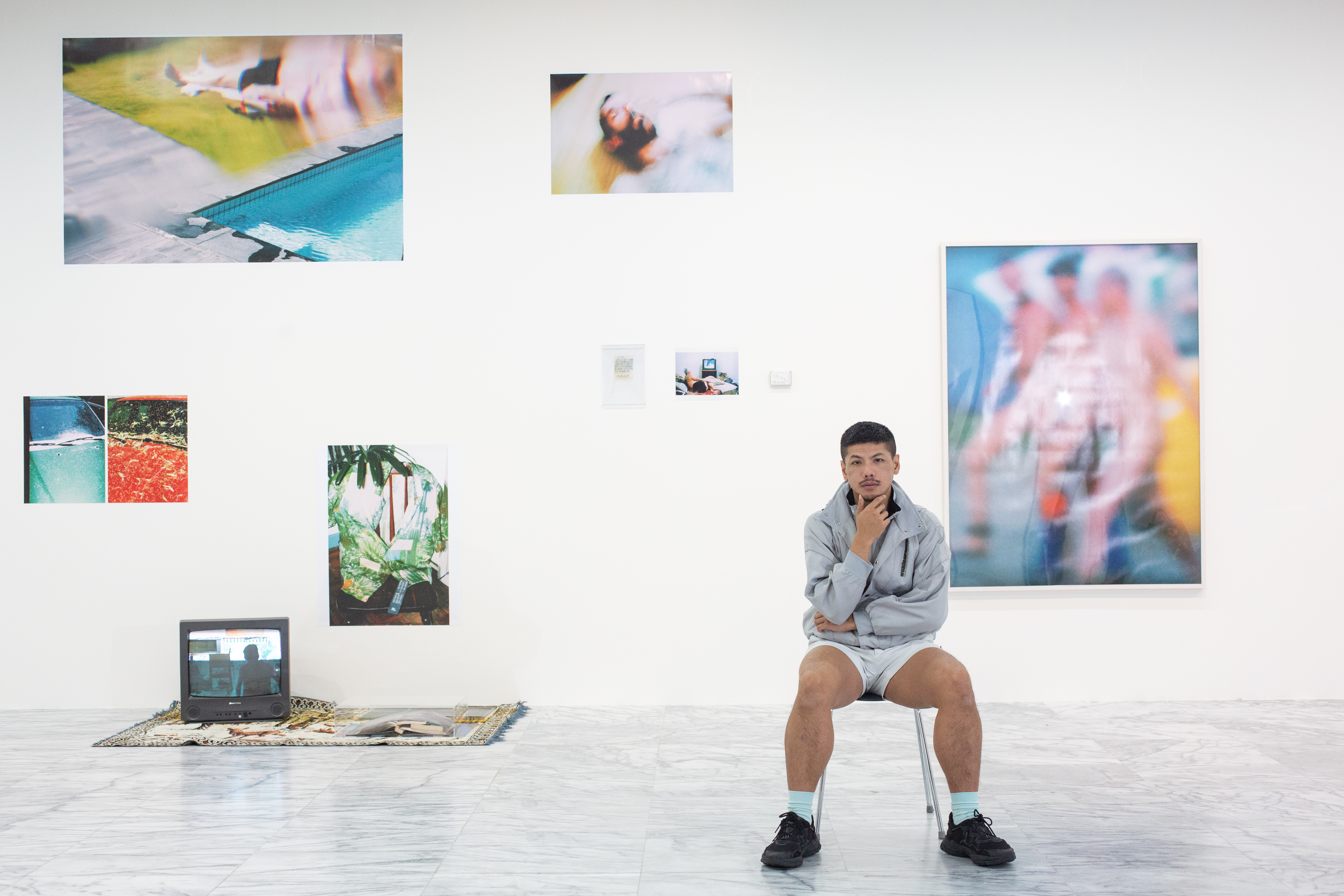 楊登棋在美術館展出台北美術獎首獎作品，背後那面牆上照片是他所拍，繽紛多彩：「照片是我的日記，我很想跟爸爸分享我的生活，但他始終難以啟齒，其實沒辦法真的對話。」