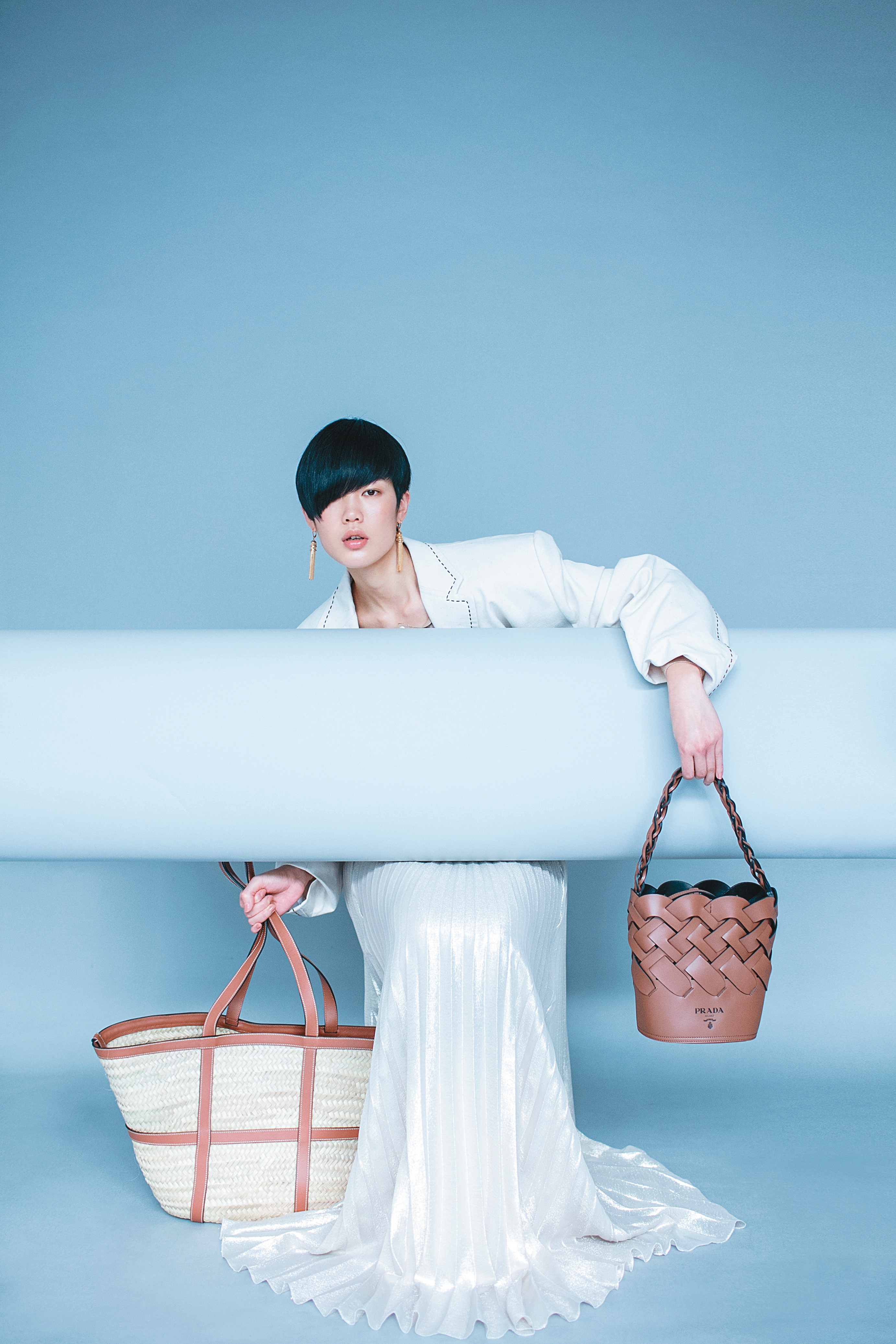 米白色西裝外套 價格店洽 by MIU MIU／白色金屬光澤百褶長裙 NT$84,400 by MAX MARA／Woven Motif編織水桶包 NT$76,000 by PRADA／Basket小牛皮大型草編包 NT$34,000 by CELINE／Maillons Triomphe 金屬黃銅流蘇造型耳環 NT$28,000 by CELINE