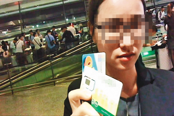 預付卡代理商（圖）拿著2張預付卡，以越南話指示移工在申辦單畫圈處簽名。（爆料影片截圖）