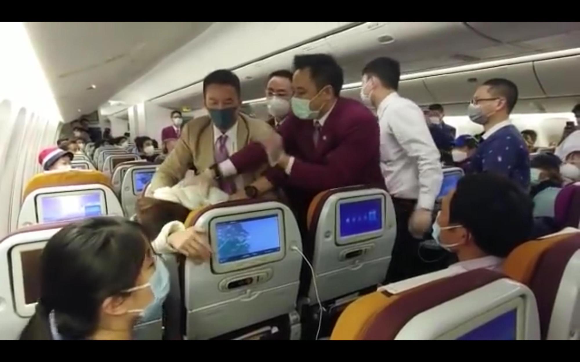 中國一名女性乘客疑因不耐泰國航空消毒程式太久,情緒失控對空服員狂咳,而後遭到壓制。(翻攝Fugu M Youtube頻道)