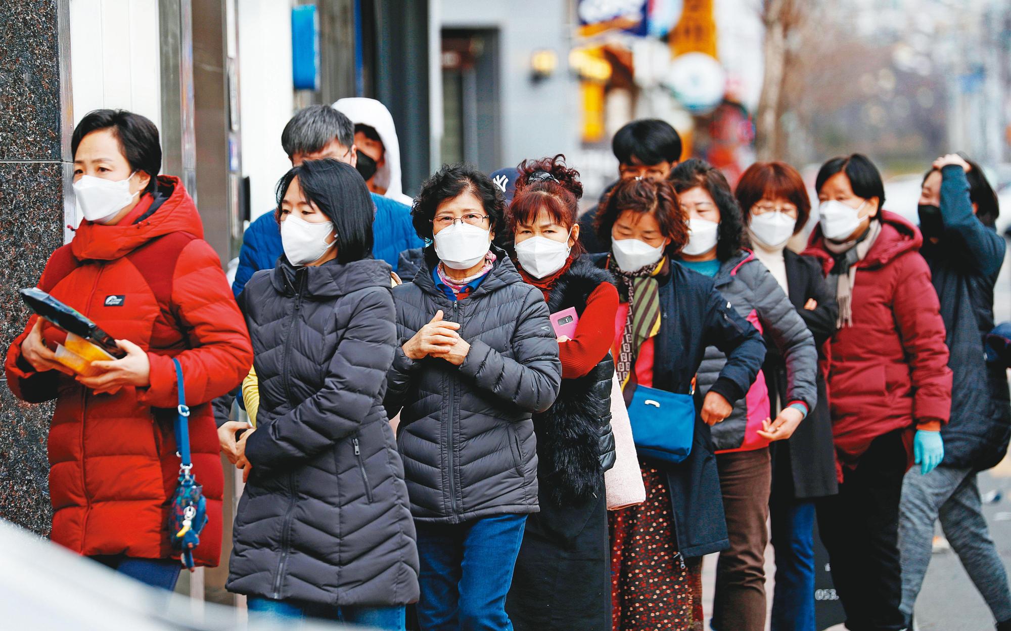 韓國確診案例暴增，9日起也推出口罩實名制，街上民眾都戴起口罩防疫。（達志影像）
