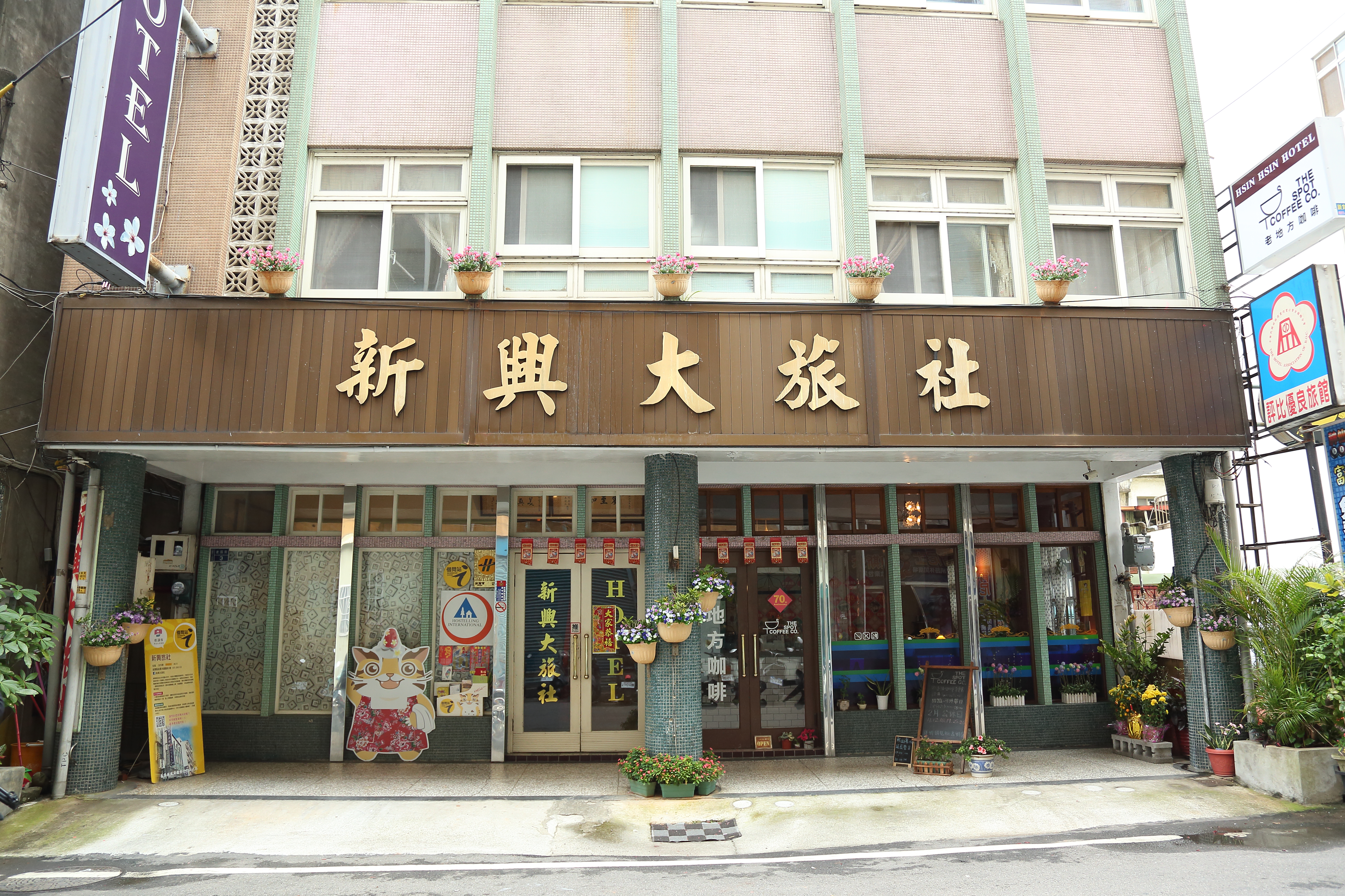 新興旅社位於苗栗火車站前一條安靜的巷弄內，茶色玻璃門上用復古的金色壓克力紙，貼著「HOTEL」的英文字樣。