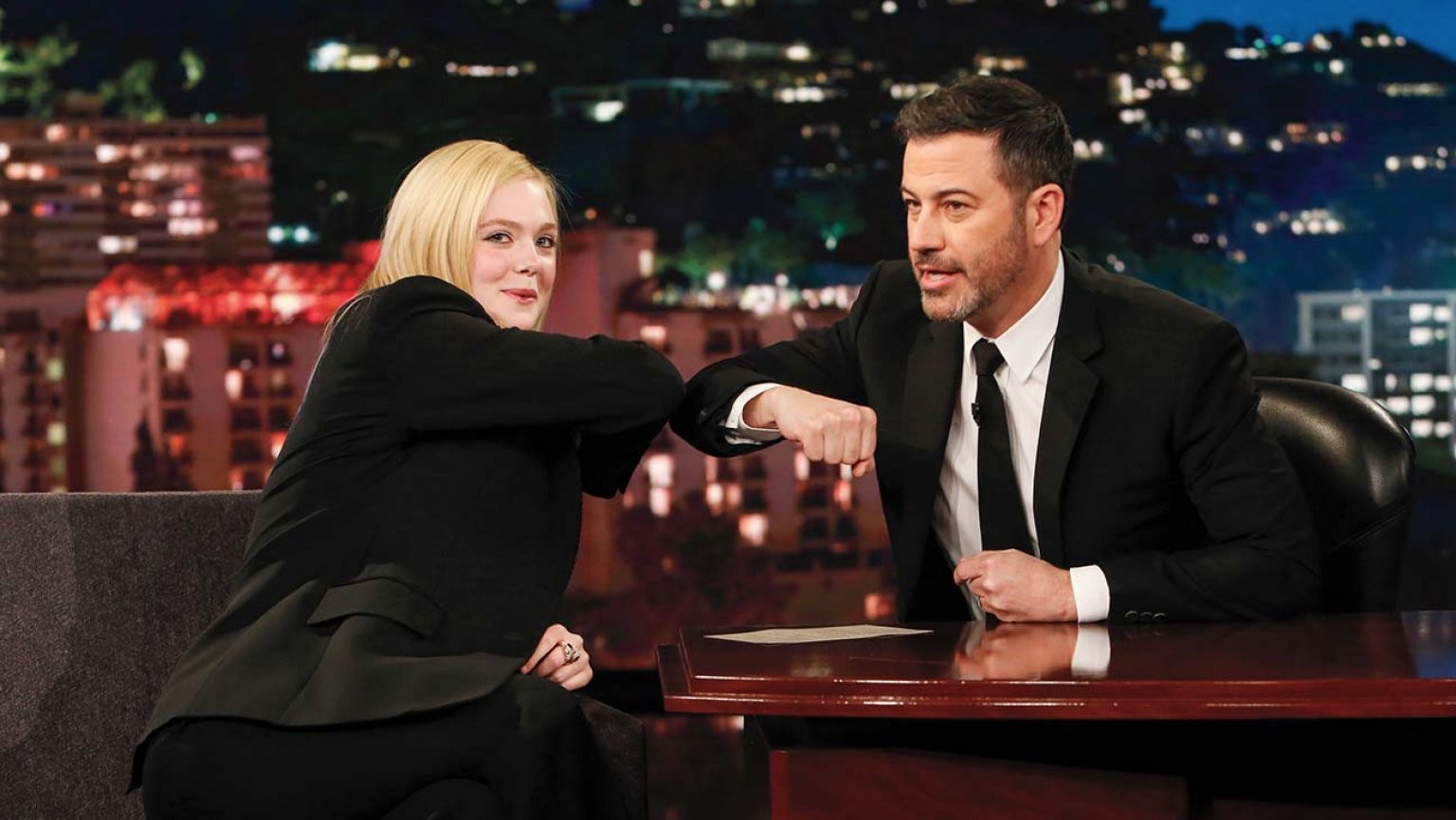 脫口秀主持人吉米基墨與女星艾兒芬妮以碰手肘代替握手。(翻攝自hollywoodreporter.com)