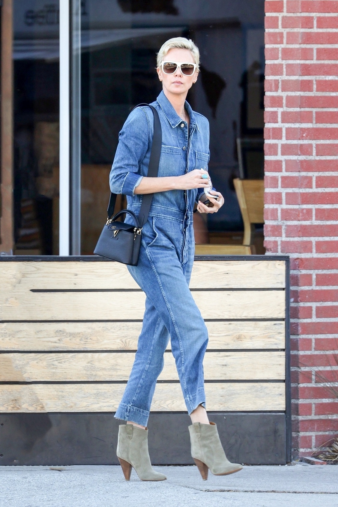 莎莉賽隆好帥氣啊！丹寧連身jumpsuit腳踩高跟短靴，搭配黑色Capucines Mini。（Louis Vuitton提供）