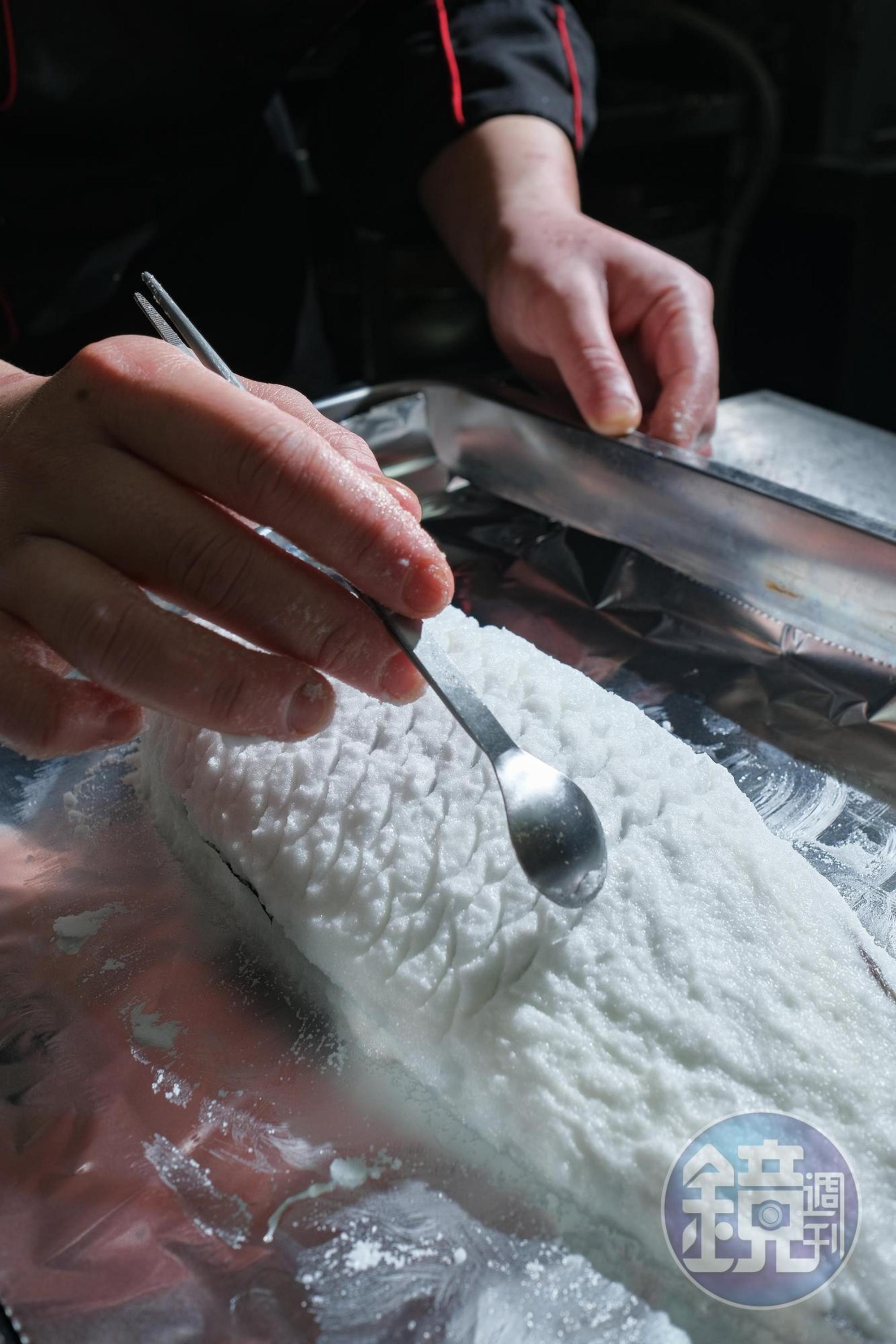 灣鯛敷上鹽與蛋白混合的模後，再用湯匙一筆筆畫出魚鱗。
