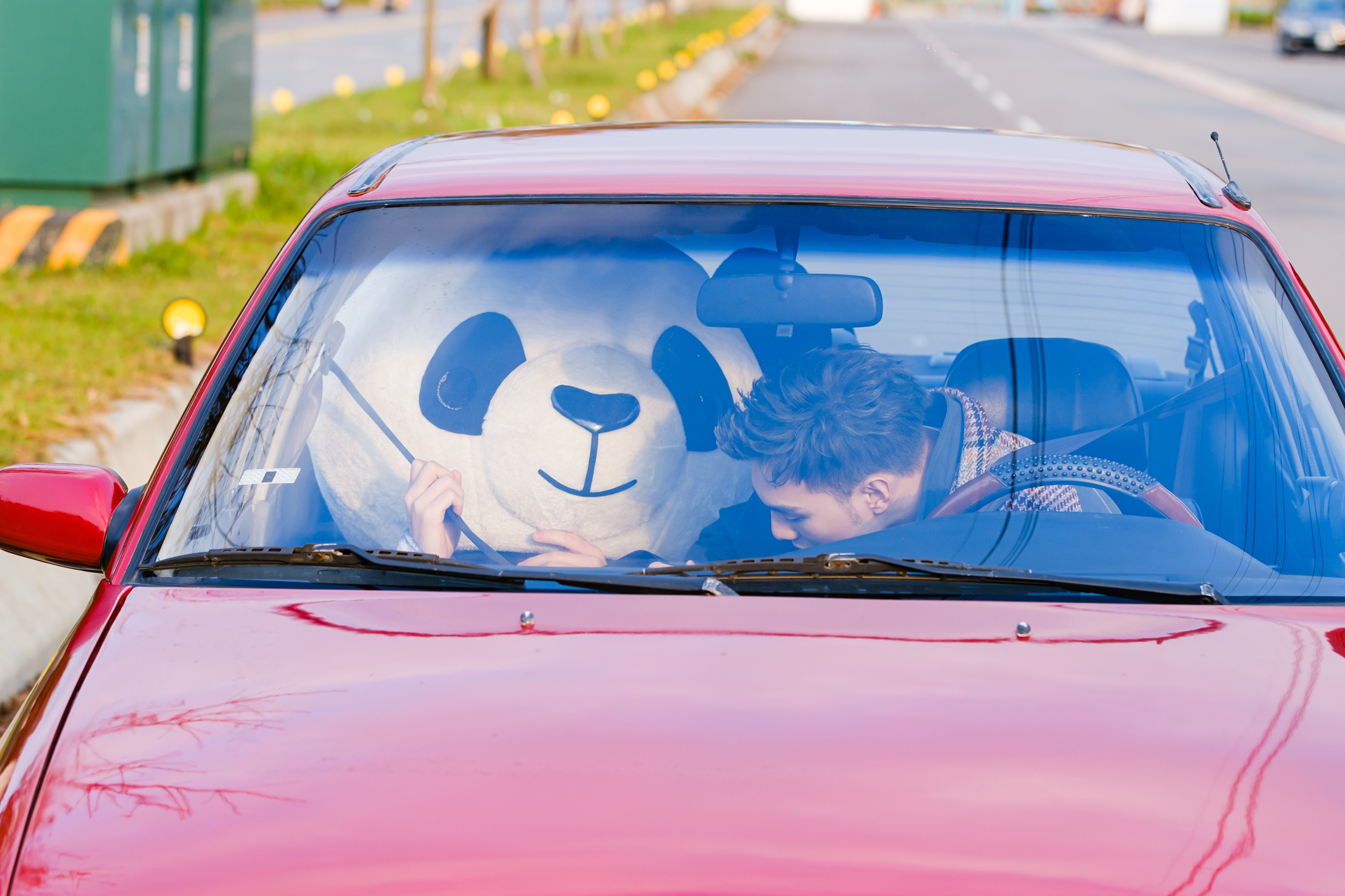 偉晉開手排車載著「熊貓人」上路，不料車子卻頻頻熄火，把戴著頭套的臨演嚇得半死。（愛貝克思）