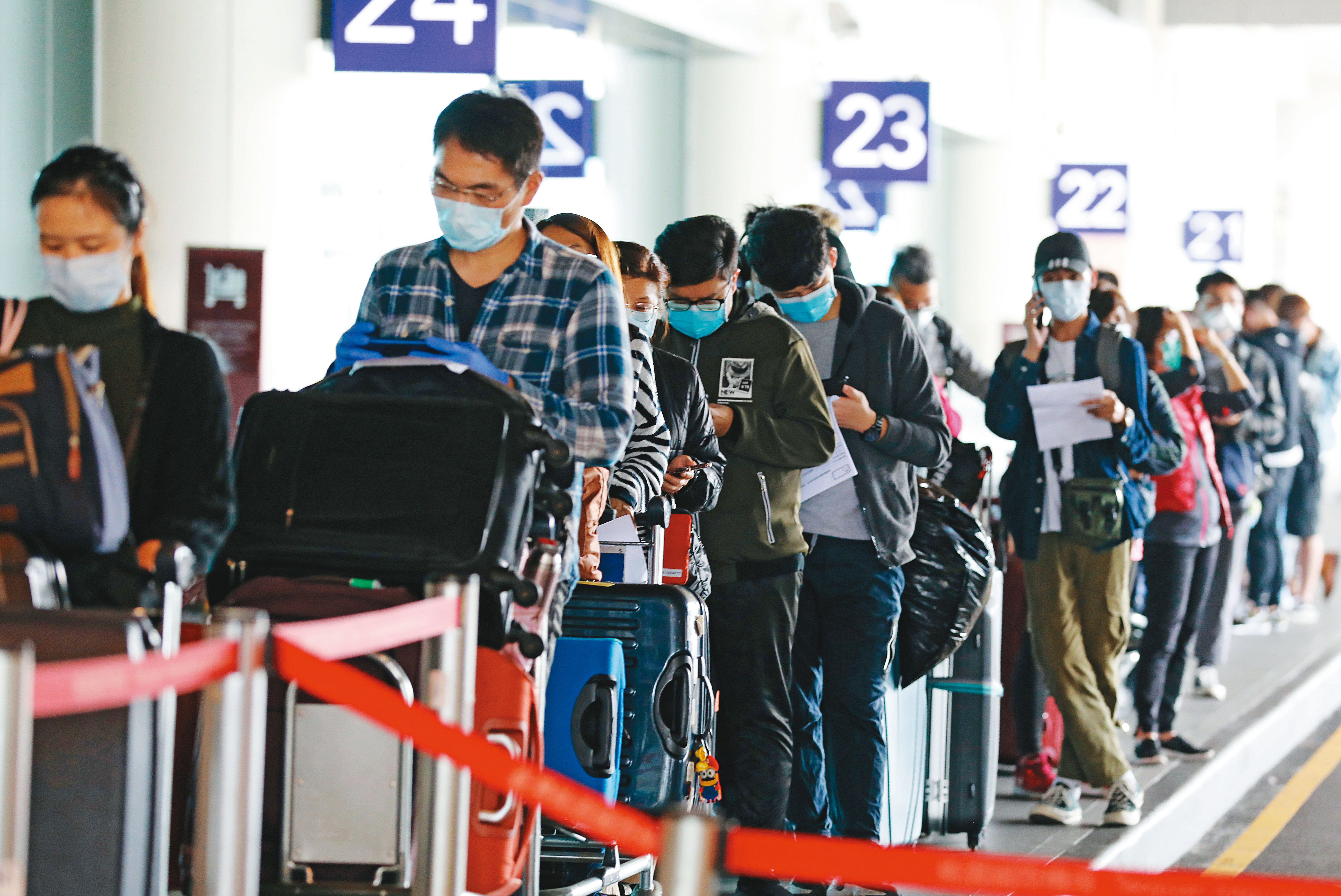 從歐美等地返國的入境者在桃園機場大排長龍（圖），等候接駁，府院升級邊境管制等防疫戰略就是要壓制這波疫情浪峰，並推遲感染爆發的高峰期。