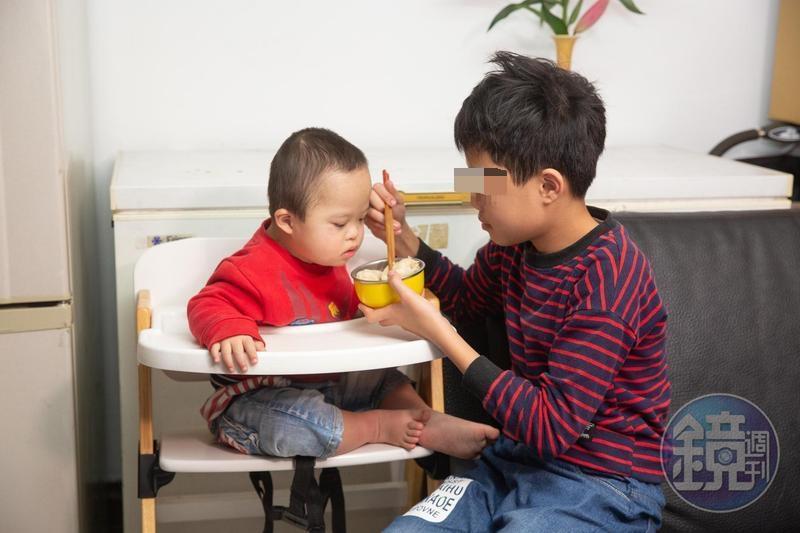 13歲的小峰(左)是母親的得力助手,悉心照顧唐寶寶弟弟。