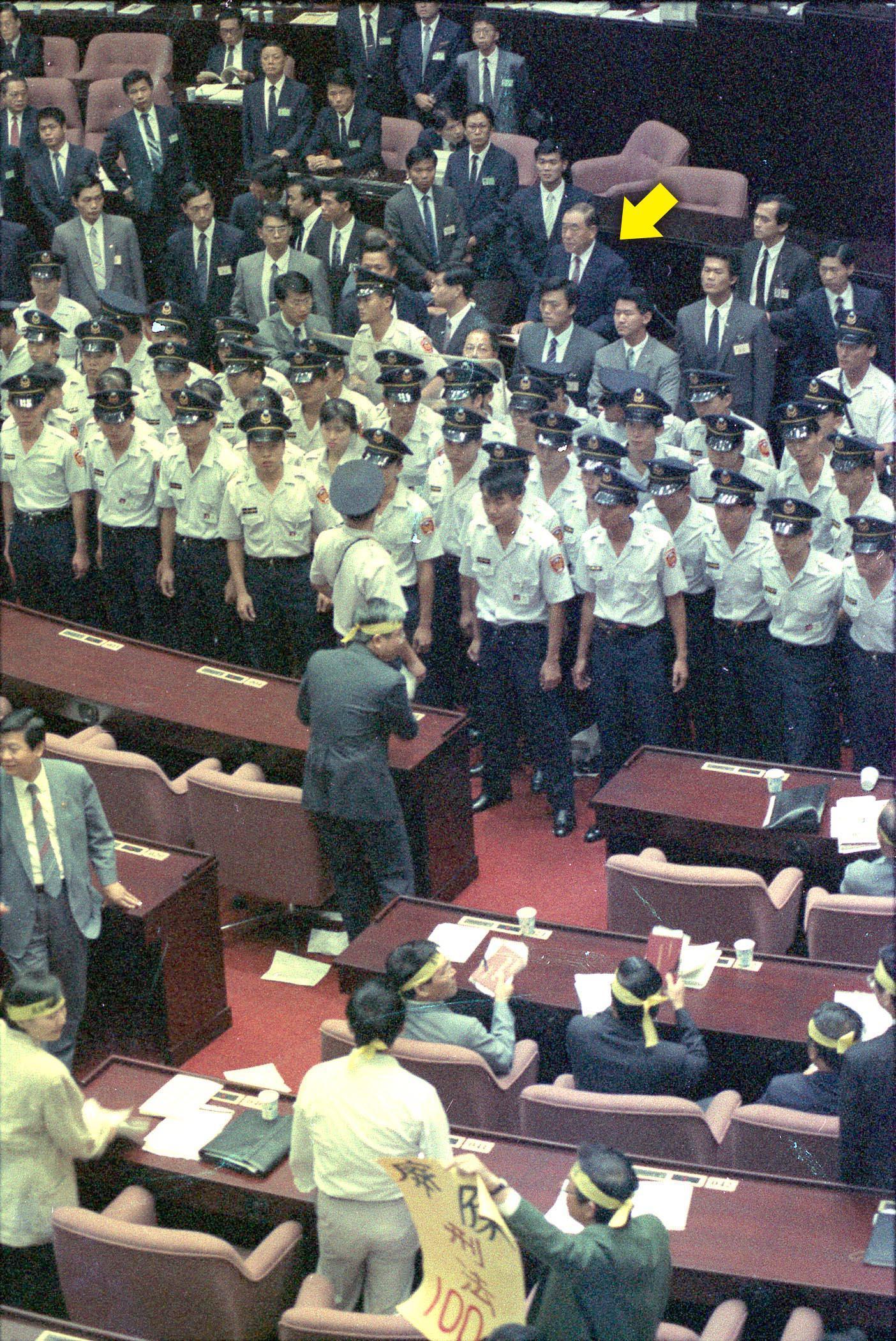1991年9月24日,立法院開議期間,時任行政院長郝柏村(箭頭處)不畏民進黨立院黨團立委的激烈抗爭,在警衛保護下,完成施政報告。(中央社)