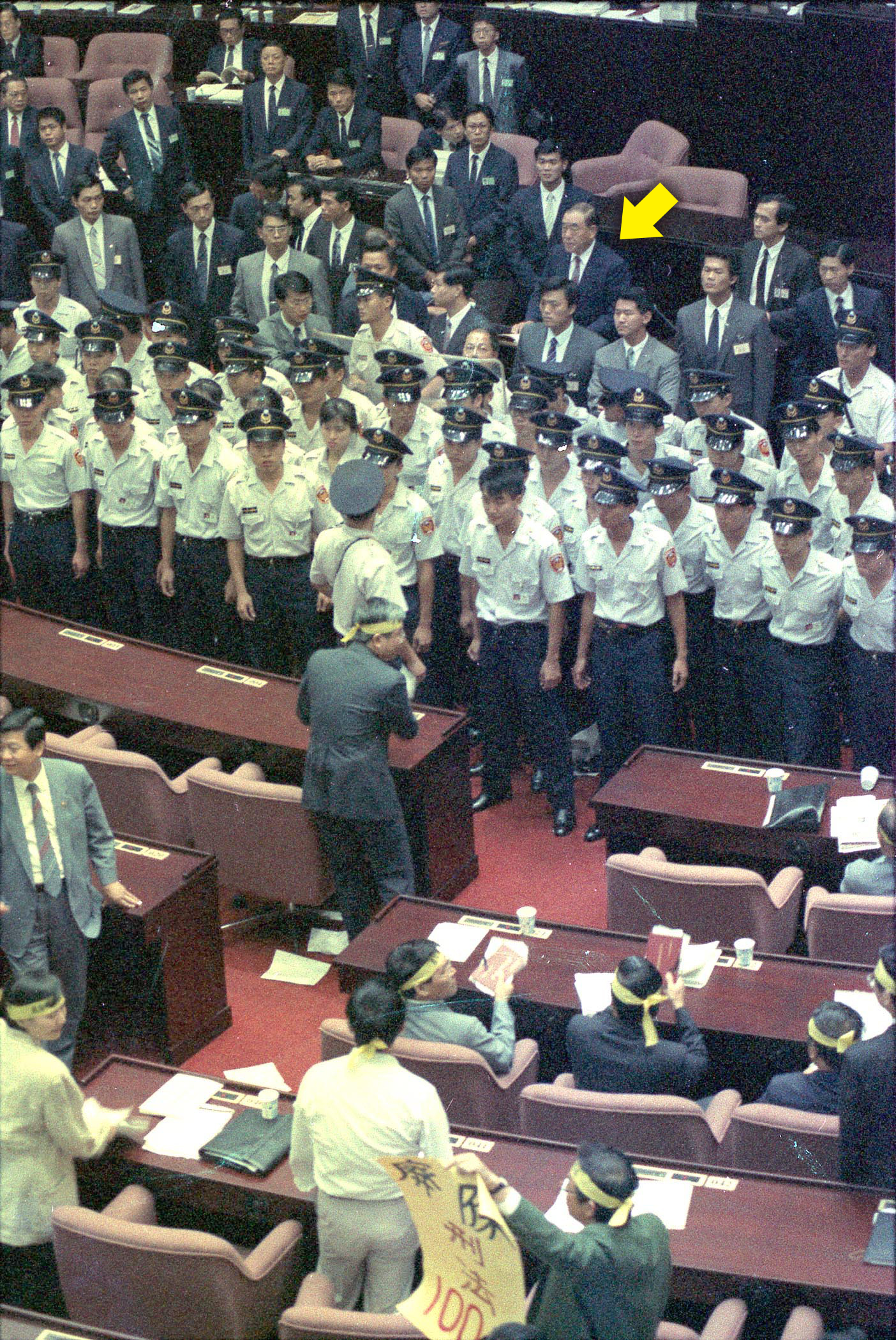 1991年9月24日，立法院開議期間，時任行政院長郝柏村（箭頭處）不畏民進黨立院黨團立委的激烈抗爭，在警衛保護下，完成施政報告。（中央社）