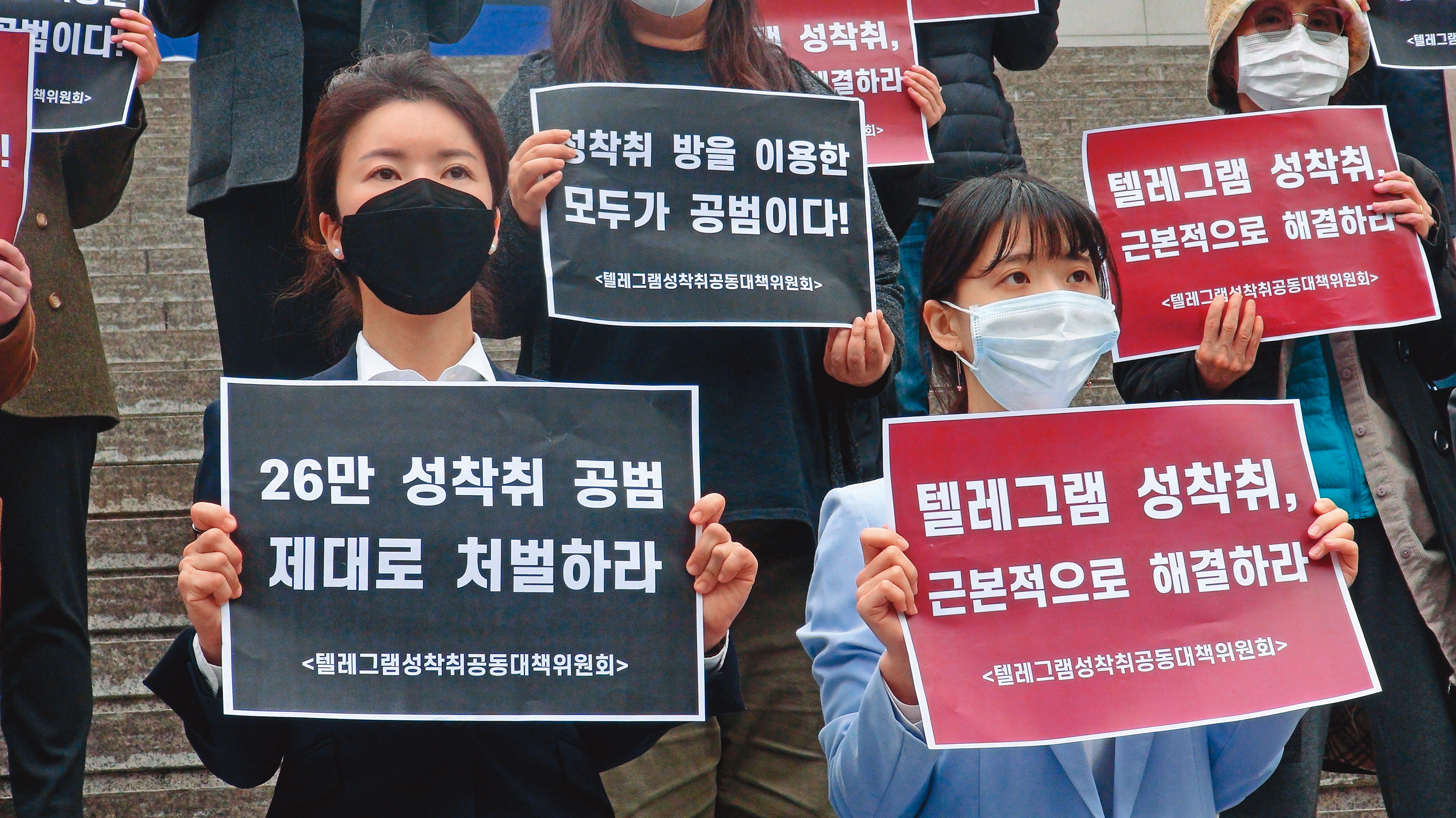 協助受害人打官司的朴藝安律師（左）及曹寅浩律師（右）。她們手持標語，訴求「好好處罰26萬名性剝削共犯」與「Telegram性剝削從根本解決」。