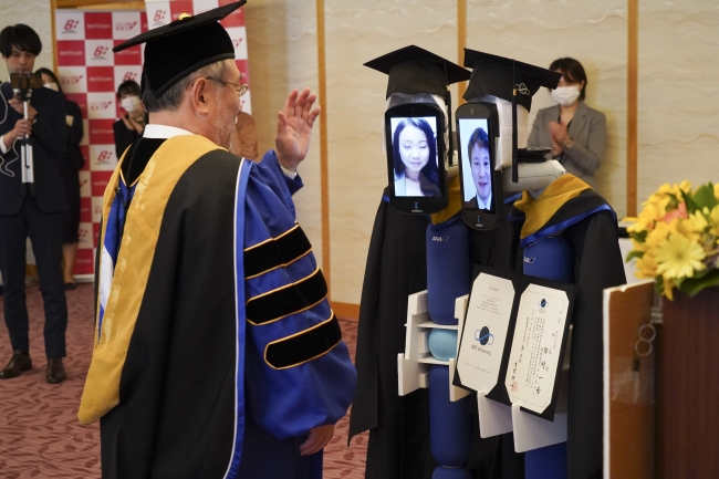 日本BBT大學創辦人兼校長大前研一頒發畢業證書給畢業生代表的機器人。（翻攝自BBT大學官網）