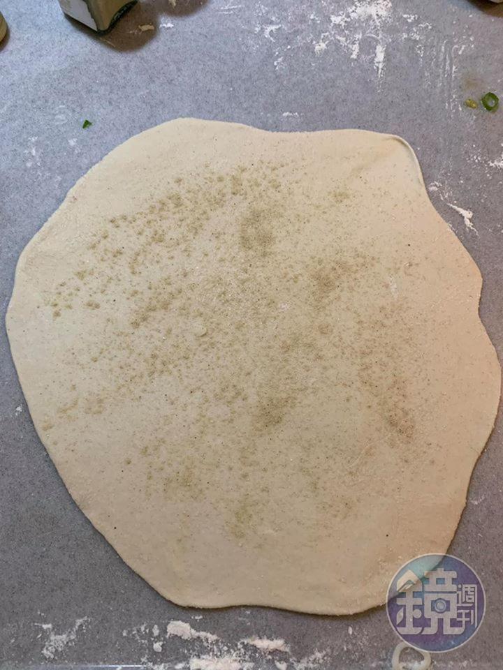 在撖平的麵團上，先撒鹽與白胡椒調味。