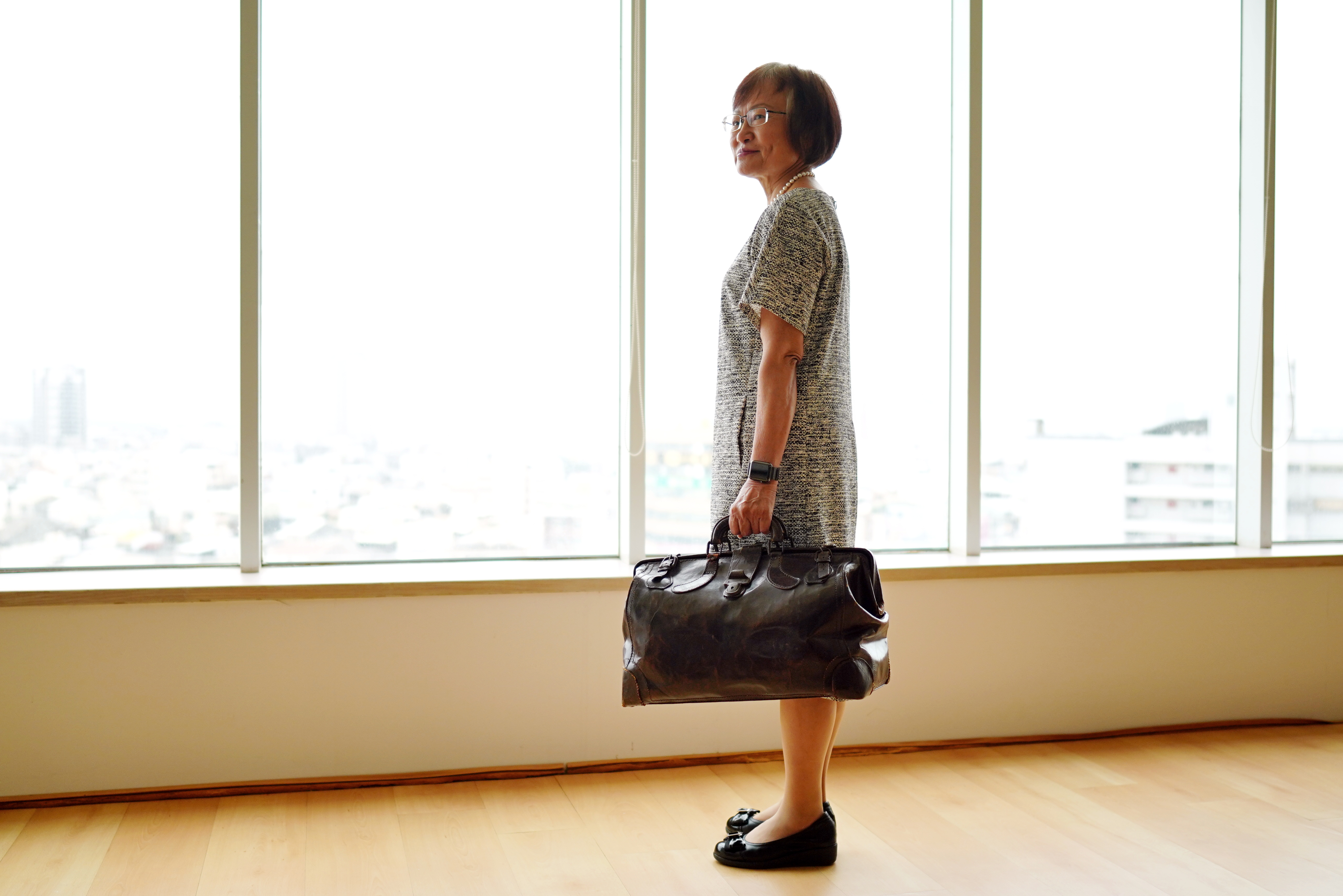 提著父親李應鏜用過的公事包，李雅容說家族所有人讀書工作都像父親一樣拚命，母親常叨唸：「別像你爸爸那樣操勞，做到死。」